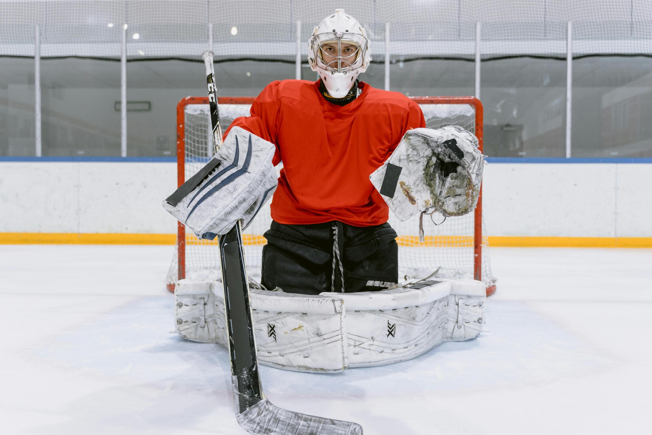 a goalie in a red jersey stands in front of the net.