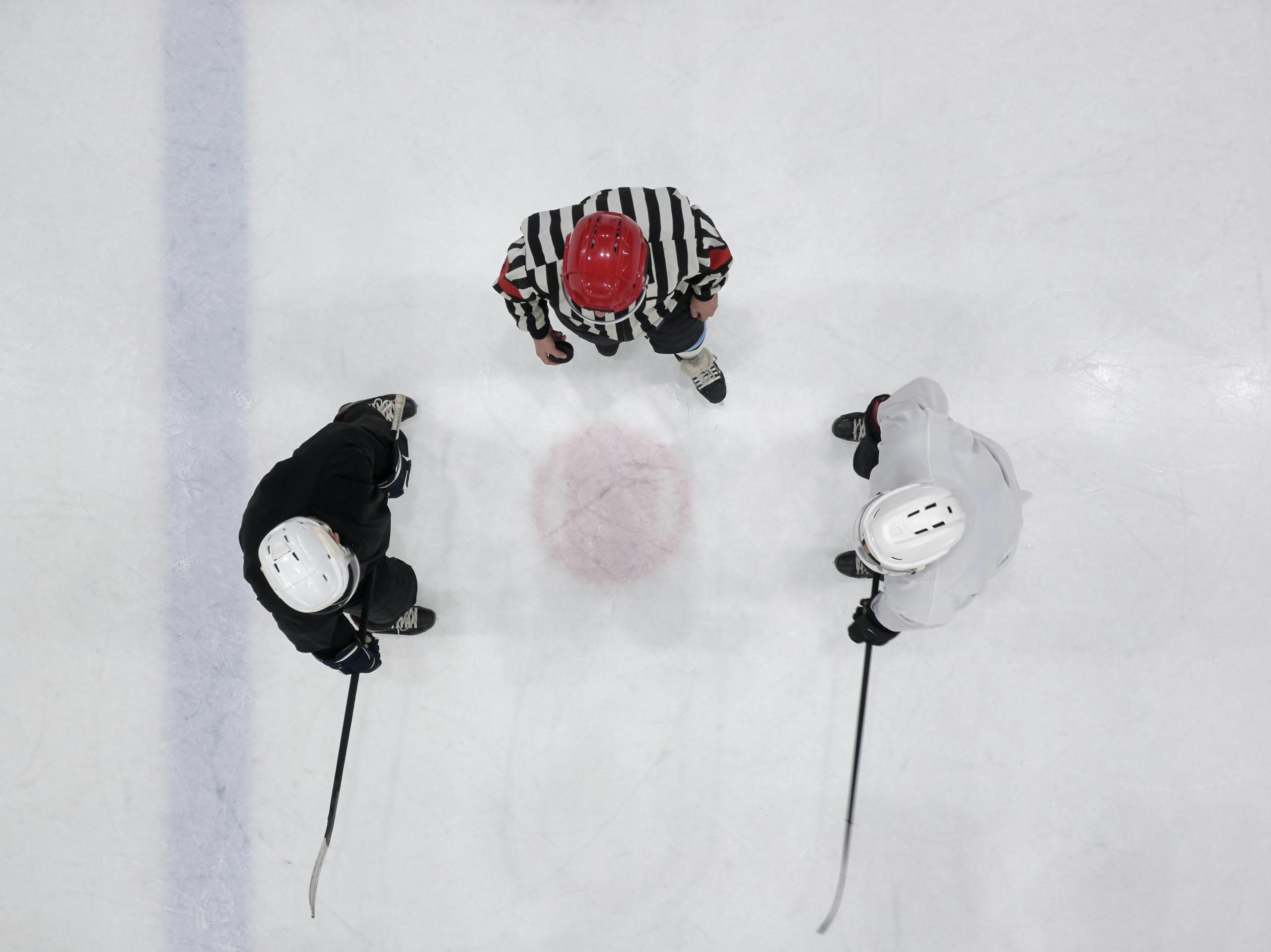 a photo taken from above an ice rink. The referee is about to drop the puck.