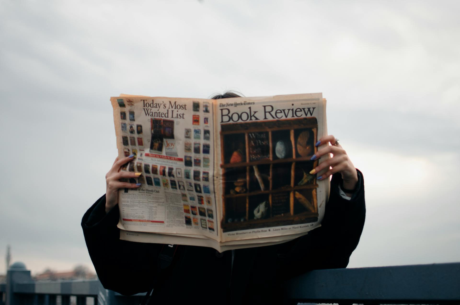 Person with multicolored nails reading a newspaper titled