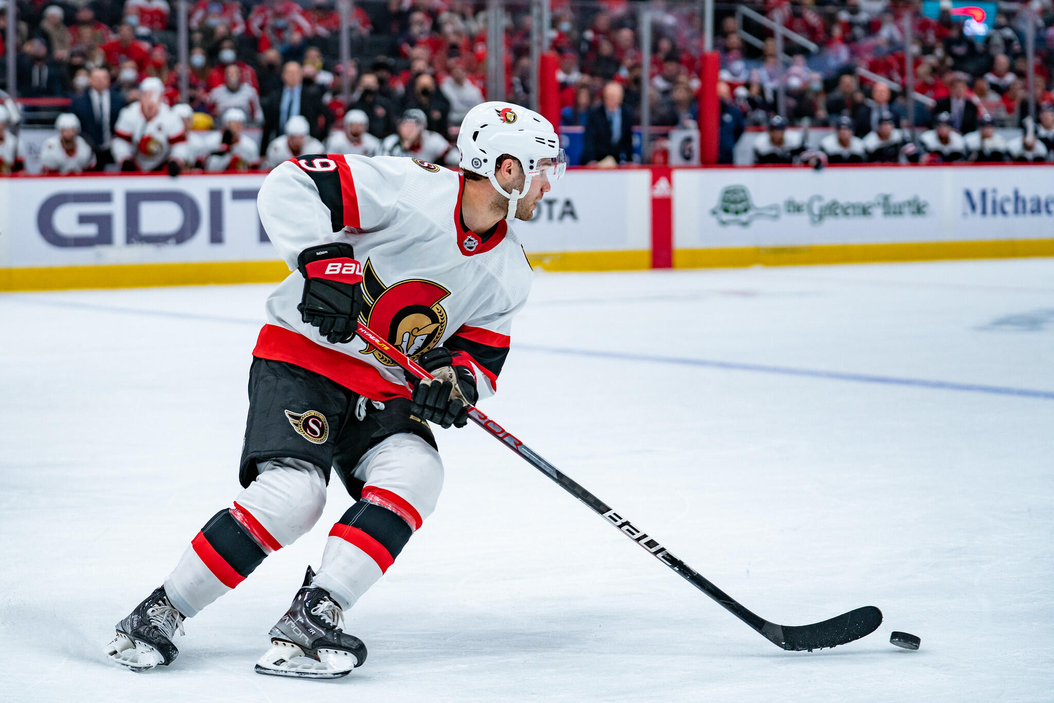Senators hockey player skating on ice while handling puck