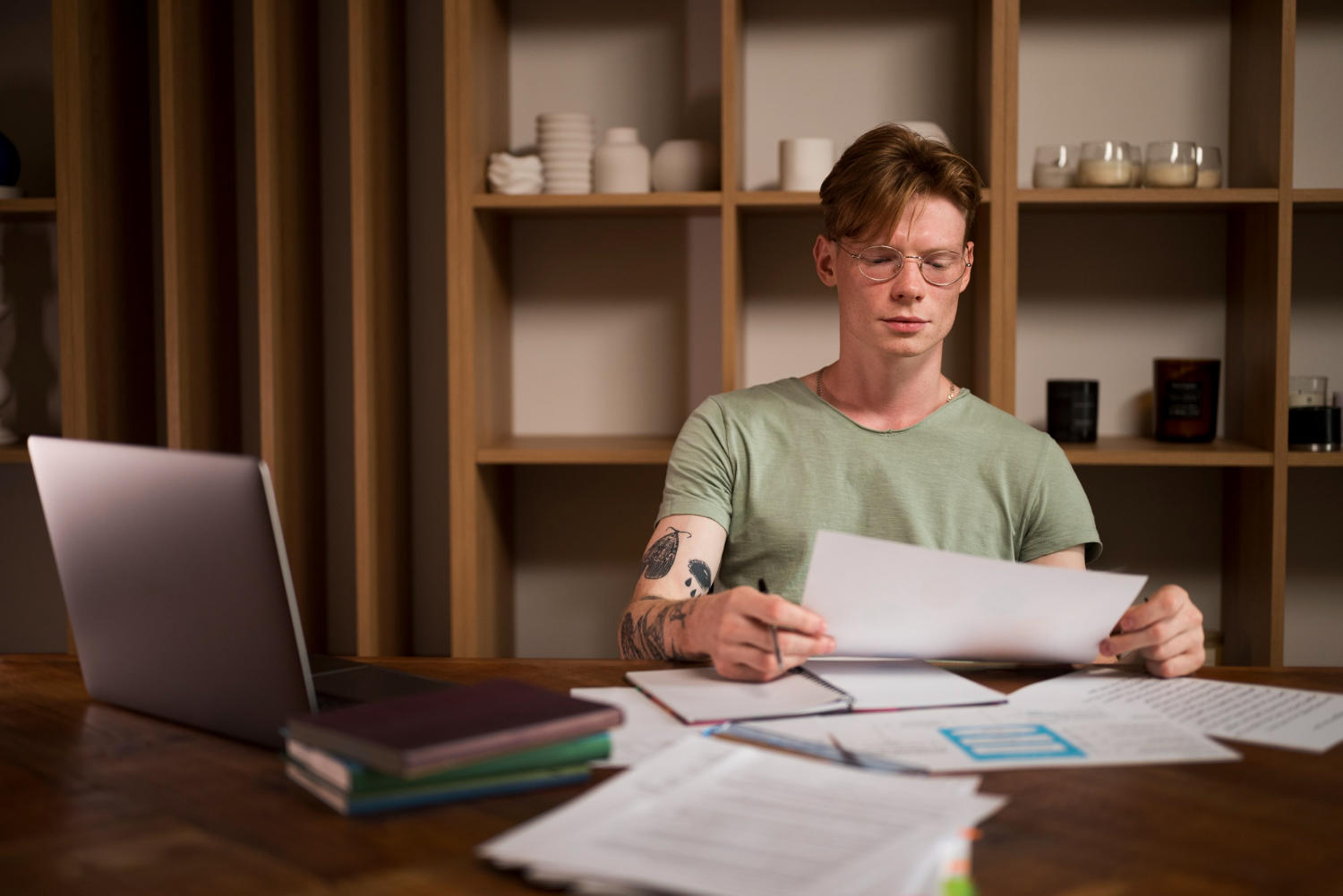 a man studying and looking at his notes in his room.