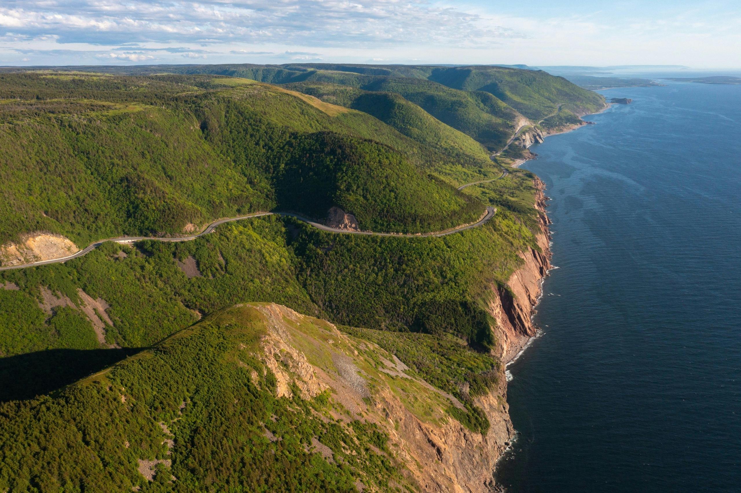 a birds-eye view of tall cliffs descending into the ocean.