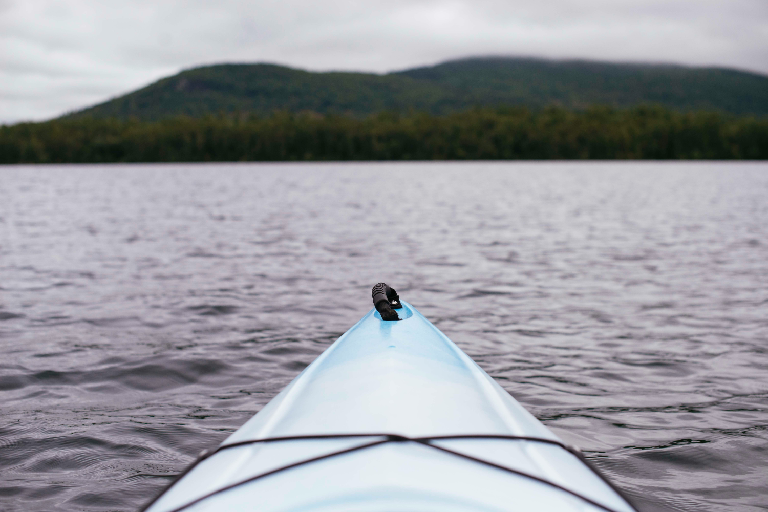 Close-up of a kayak on a lake with forested hills in the background in Gros Morne National Park.