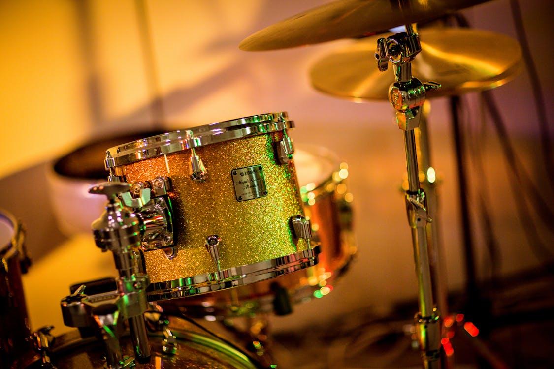 The photograph shows a drum and other golden and glittery musical instruments. 