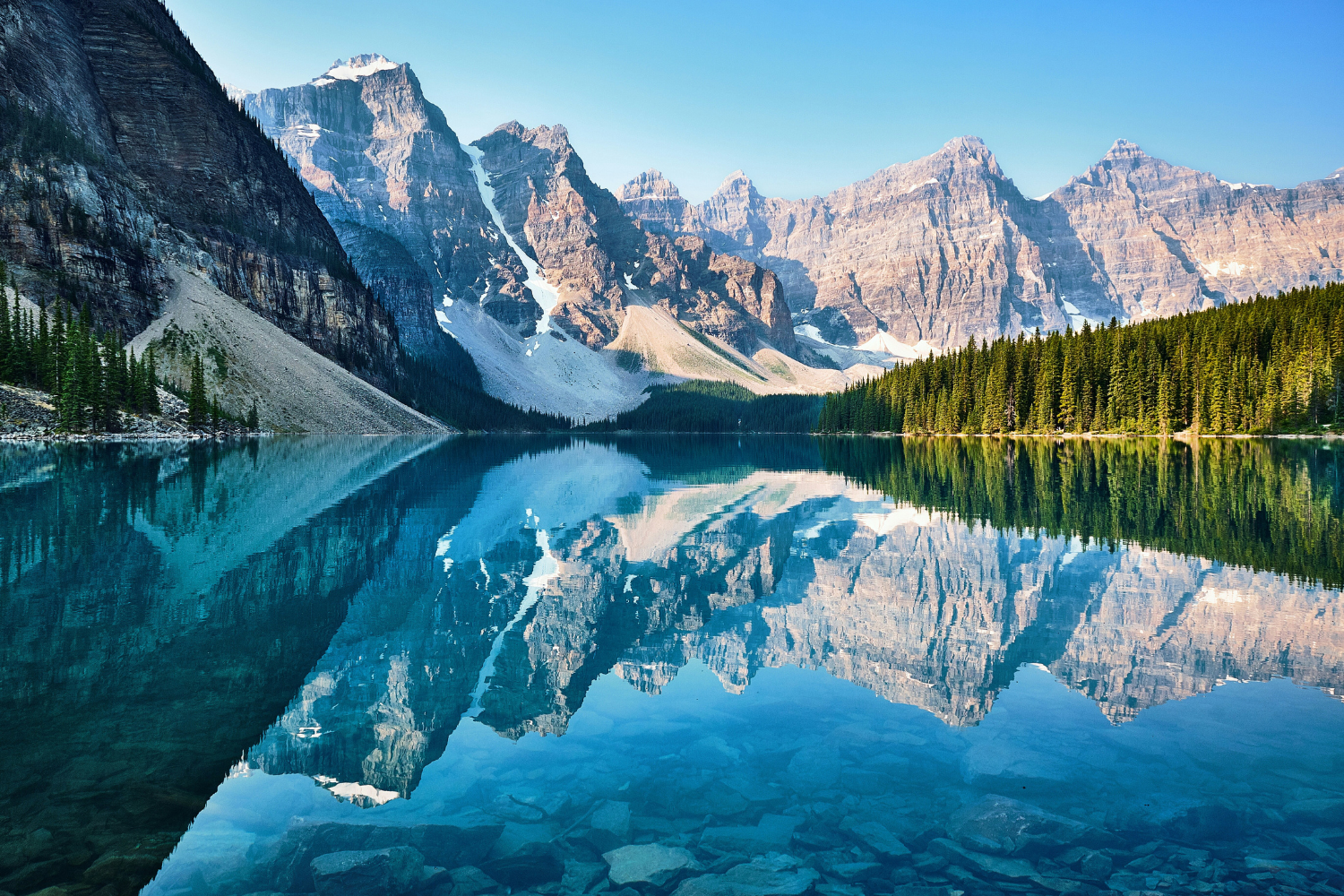 Mirror-like reflections of rugged mountain peaks and turquoise waters at Moraine Lake in Banff National Park.