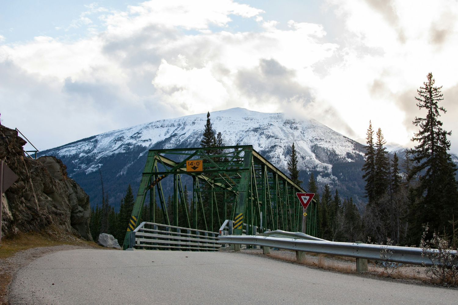Green steel industrial crossing with the snowcapped mountains of Jesper National Park in the background.