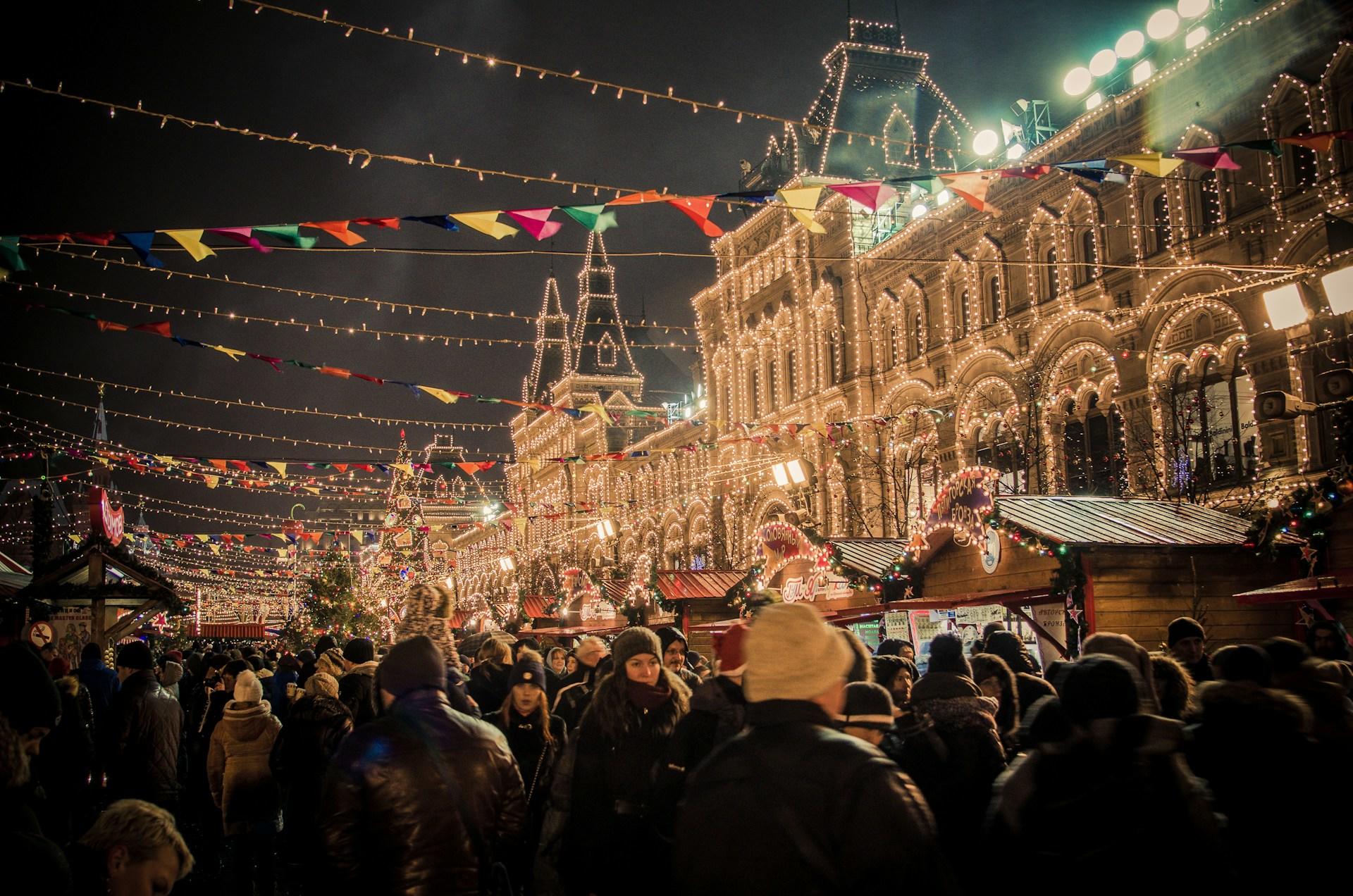 A festive outdoor Christmas market with illuminated buildings and colorful bunting.