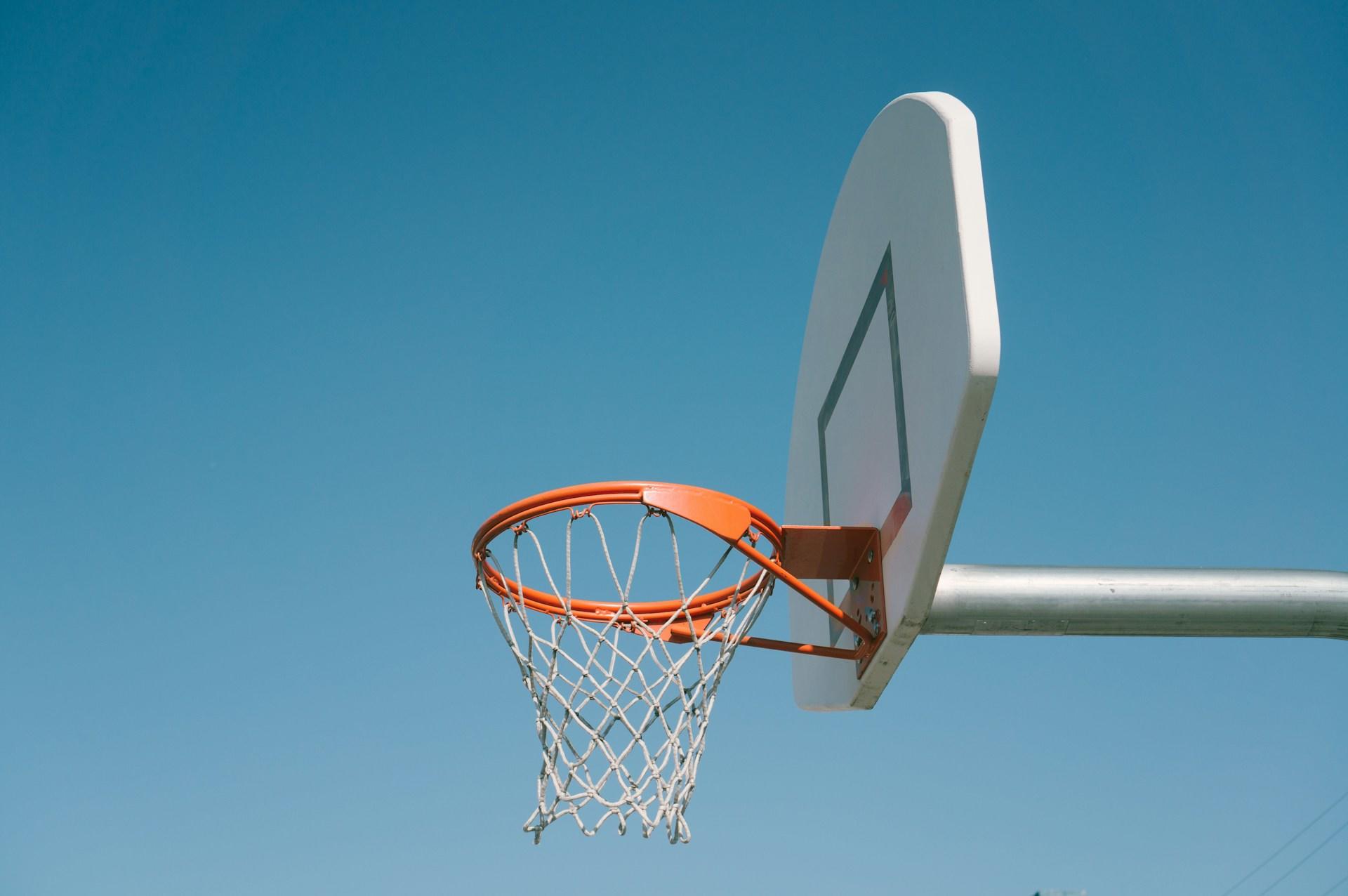 orange basketball hoop attached to a white backboard with blue skies in the background.