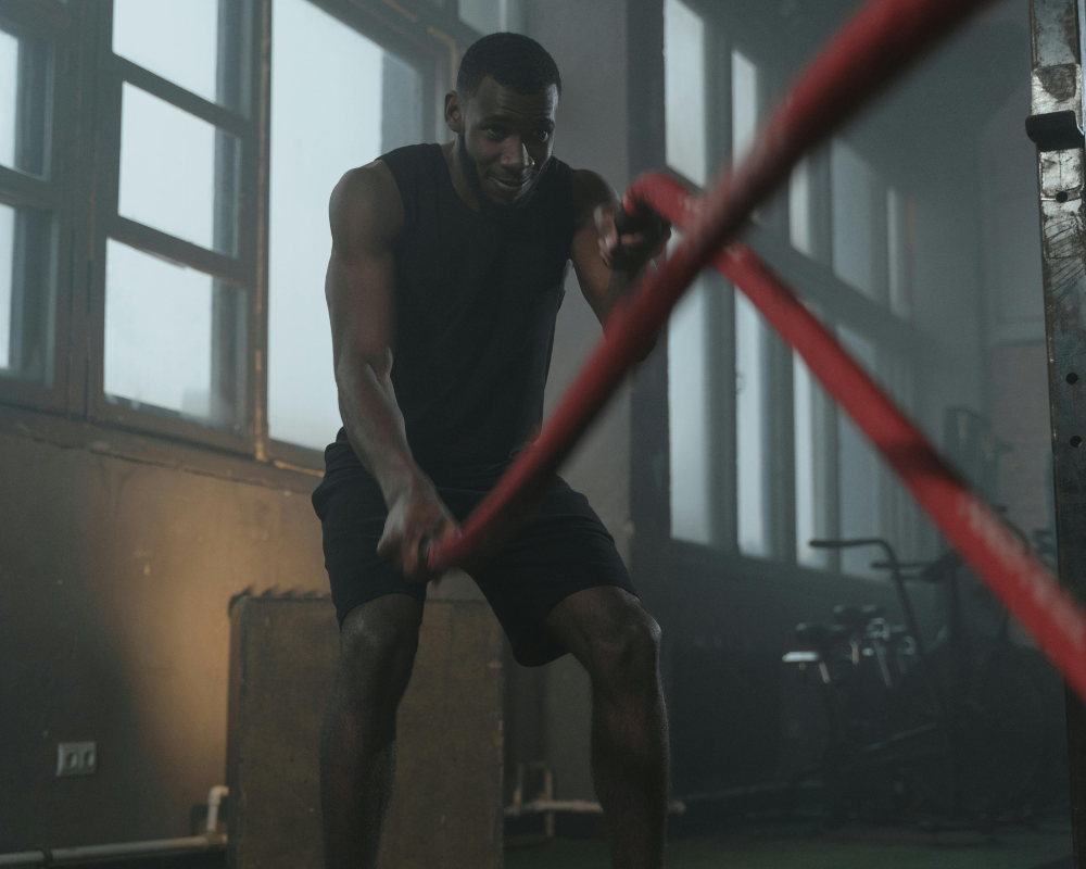 A man performing battle rope exercises during a high-intensity interval training (HIIT) session.