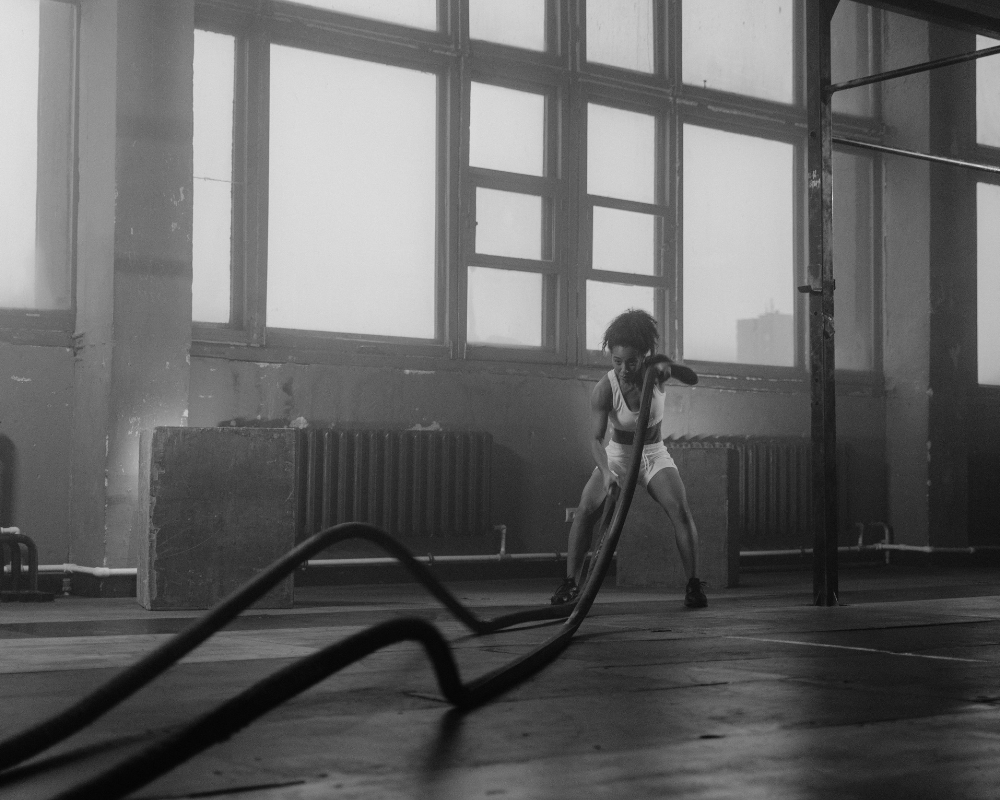 A person performing an intense HIIT workout with battle ropes in a fitness studio in Montreal.