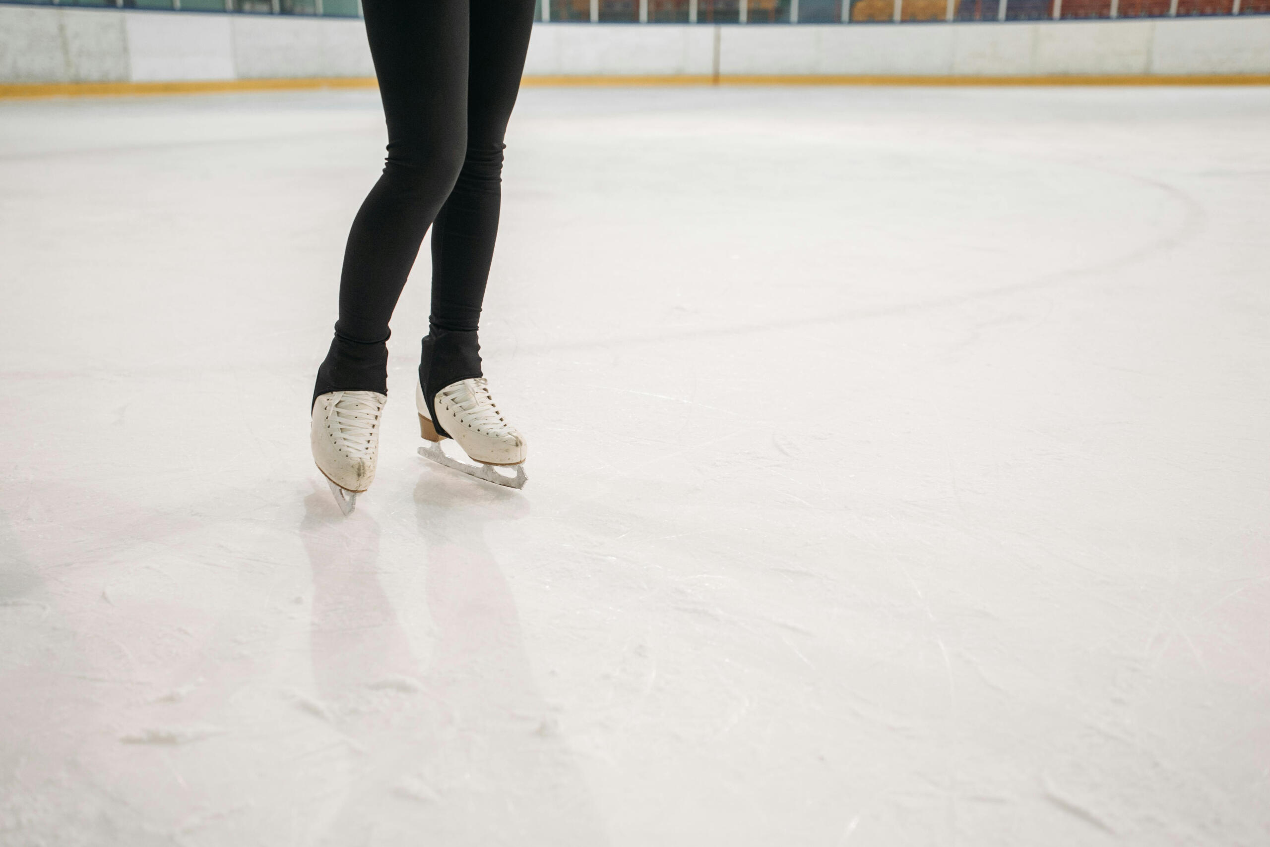 A figures skater stands in an indoor rink.