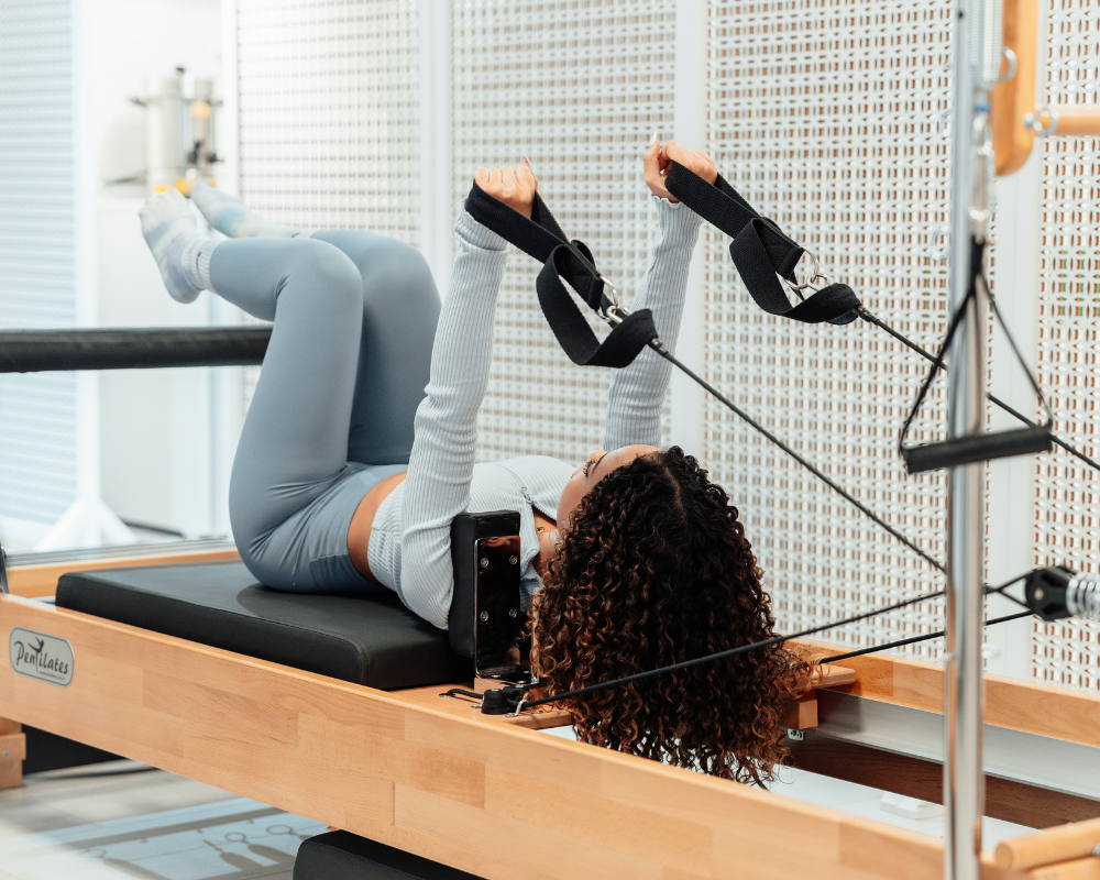 A person practicing Pilates on a reformer machine at a studio in Montreal, focusing on core strength and flexibility.