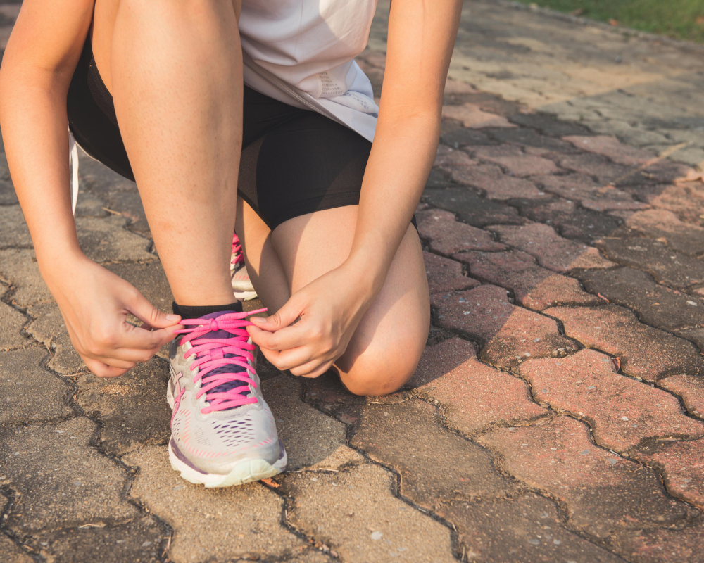 A runner in Montreal, tying her shoes and preparing for a running club session outdoors.