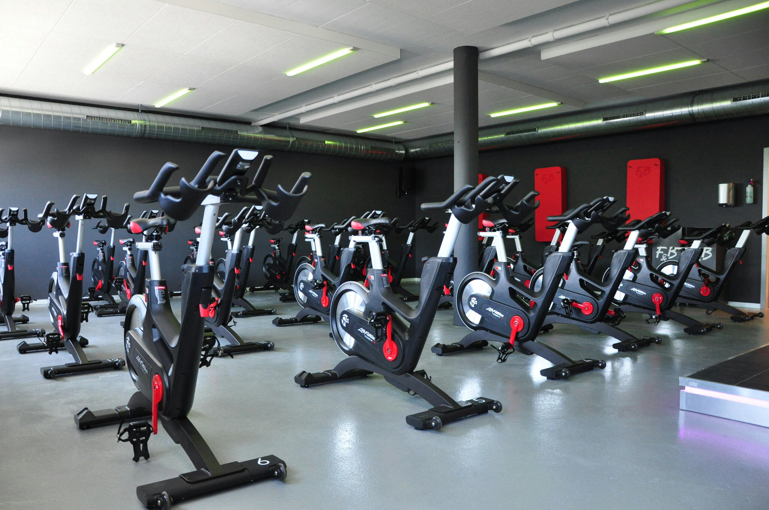 A row of stationary spin bikes arranged in a fitness studio with a modern design and dim lighting.