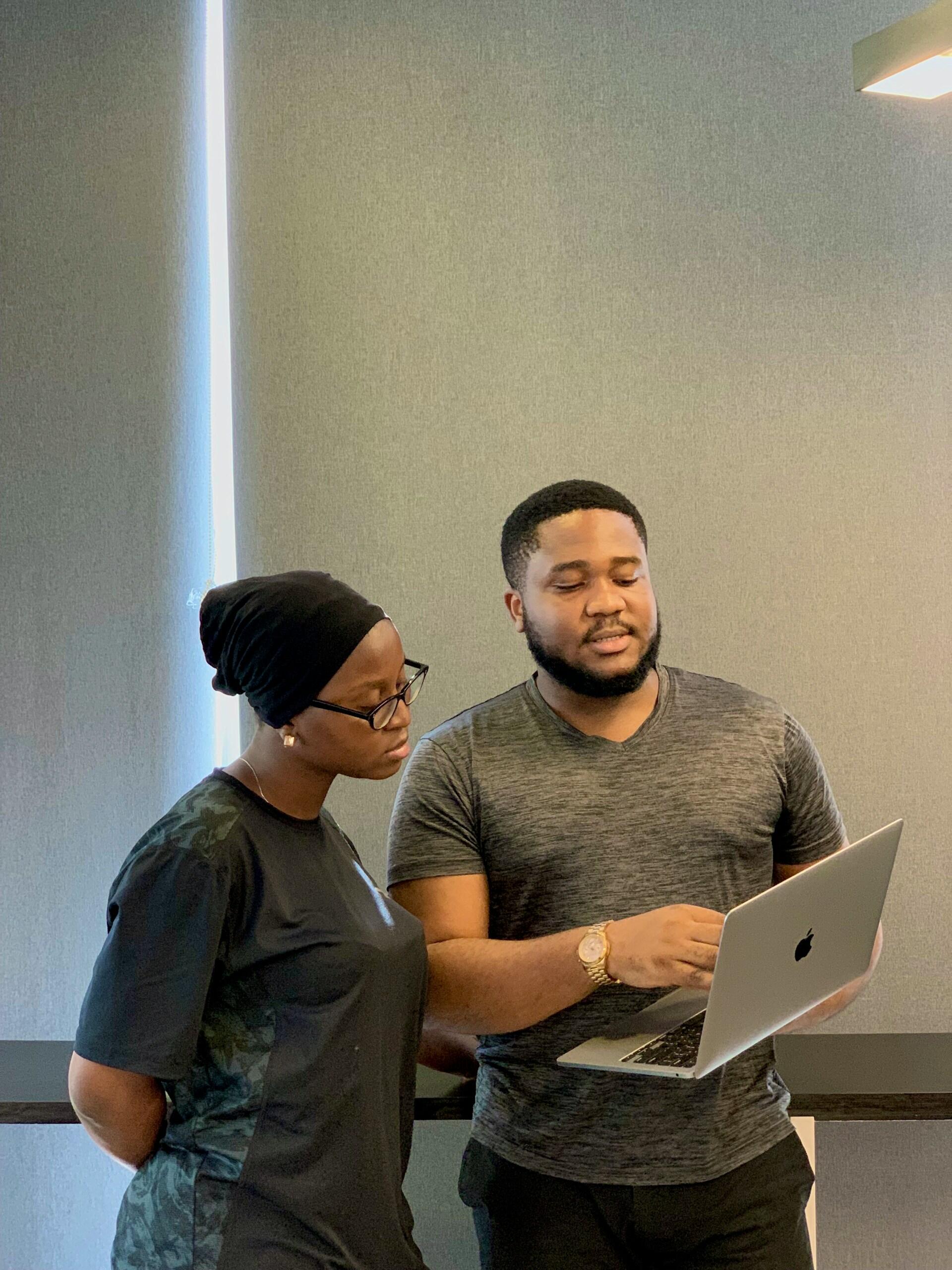 a male tutor explaining something to a female student wihle pointing on a laptop