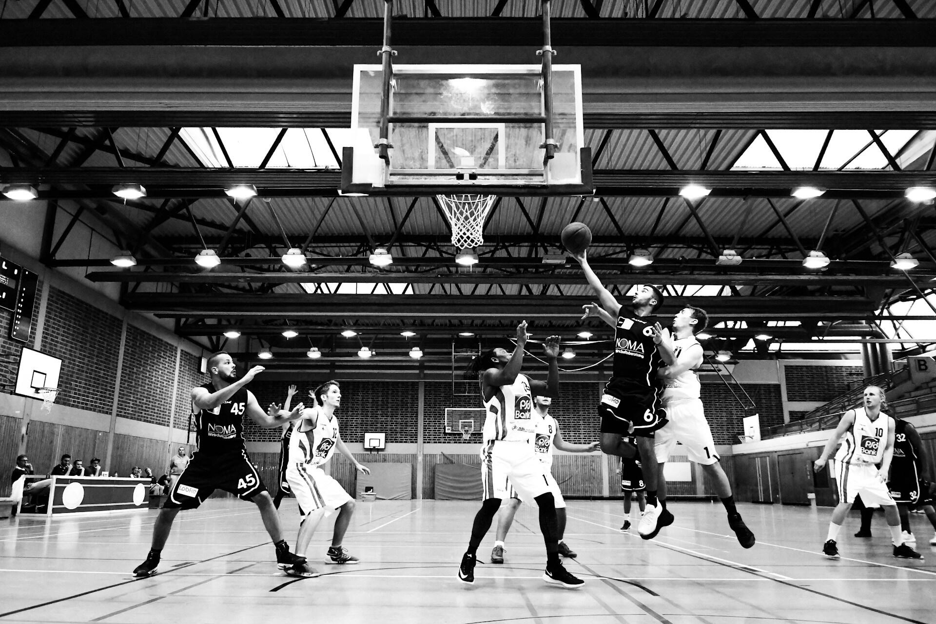 Black and white photo of a basketball game in an indoor court.