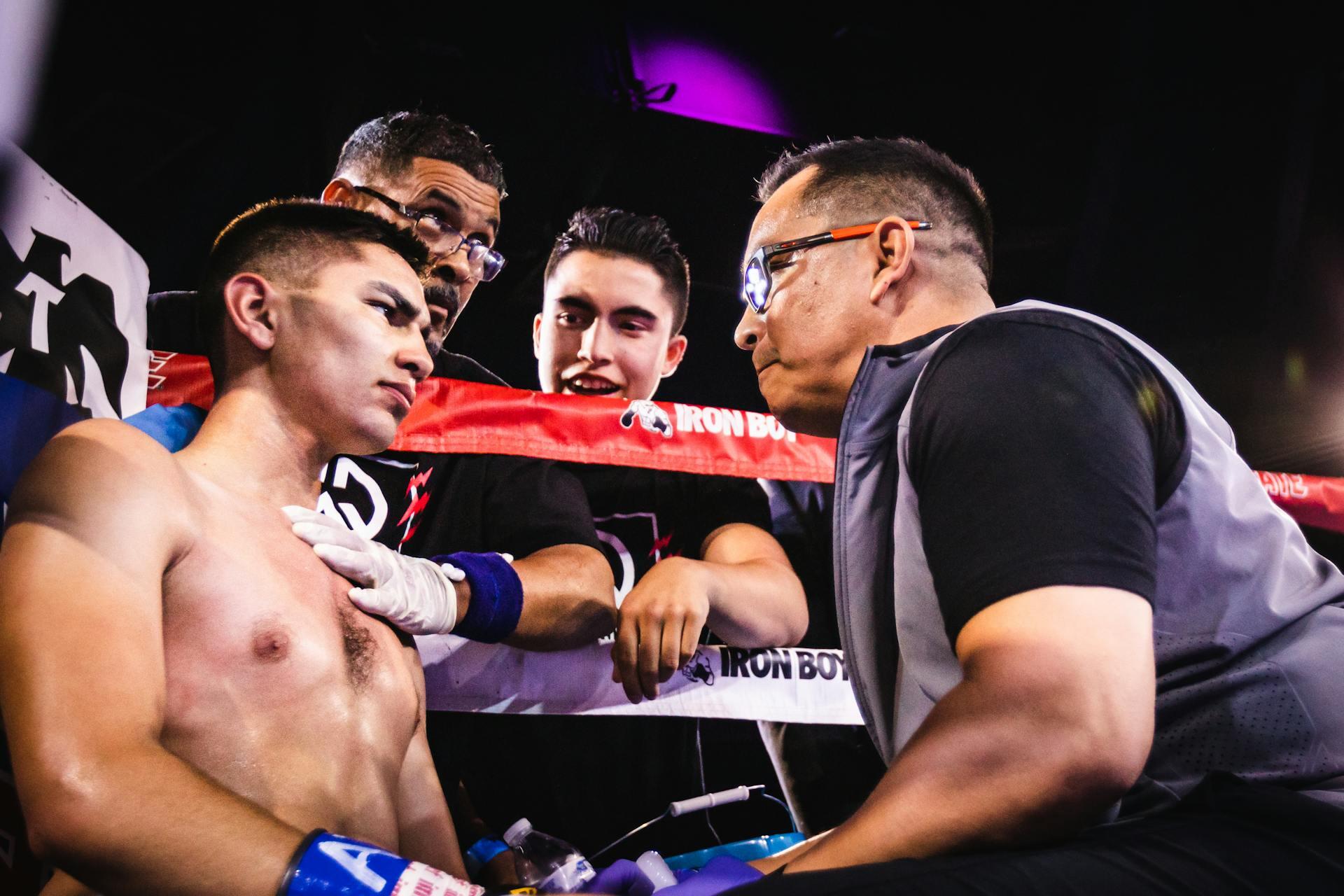 Boxer with trainer and team in ring corner.
