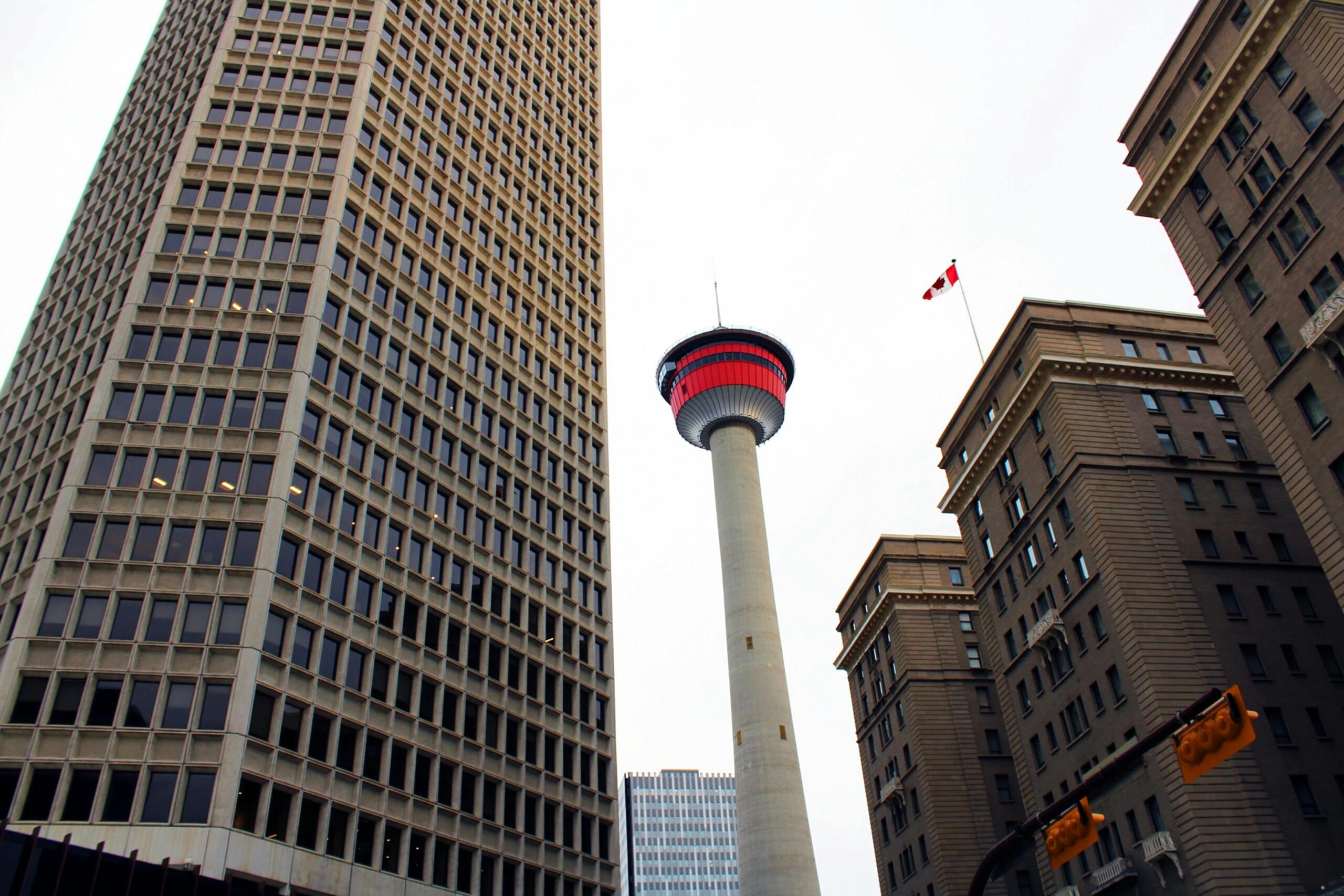 A futuristic tower is at the centre of the photo, lit up in red. Modern and traditional skyscrapers surround the tower.