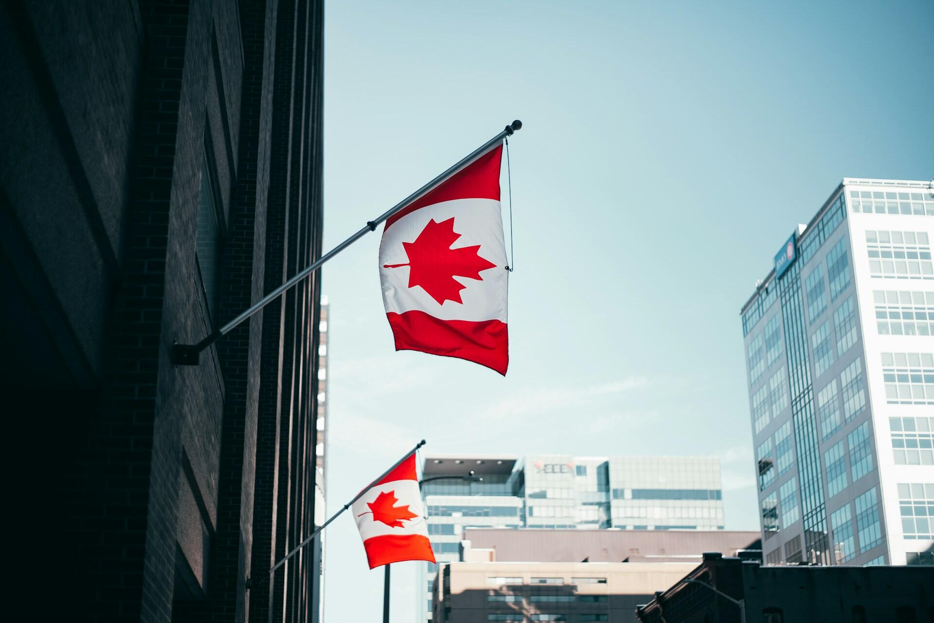 two Canadian flags hanging from a building