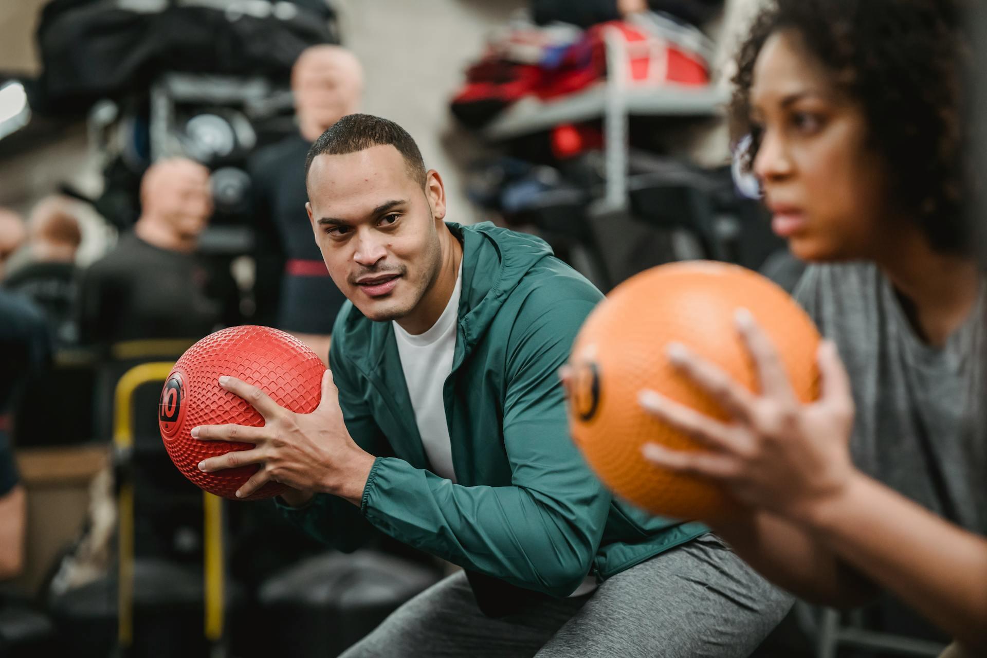 Coach and female trainee squatting with weighted medecine balls.