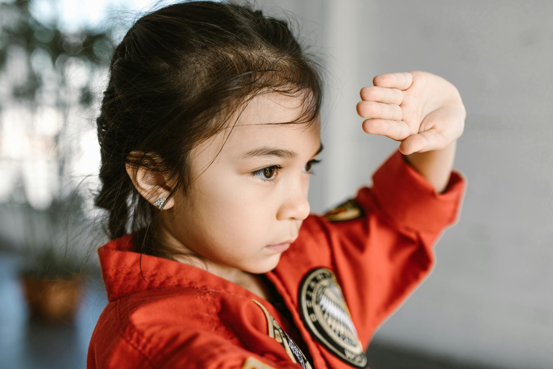 The photograph shows a girl in a red martial arts uniform.