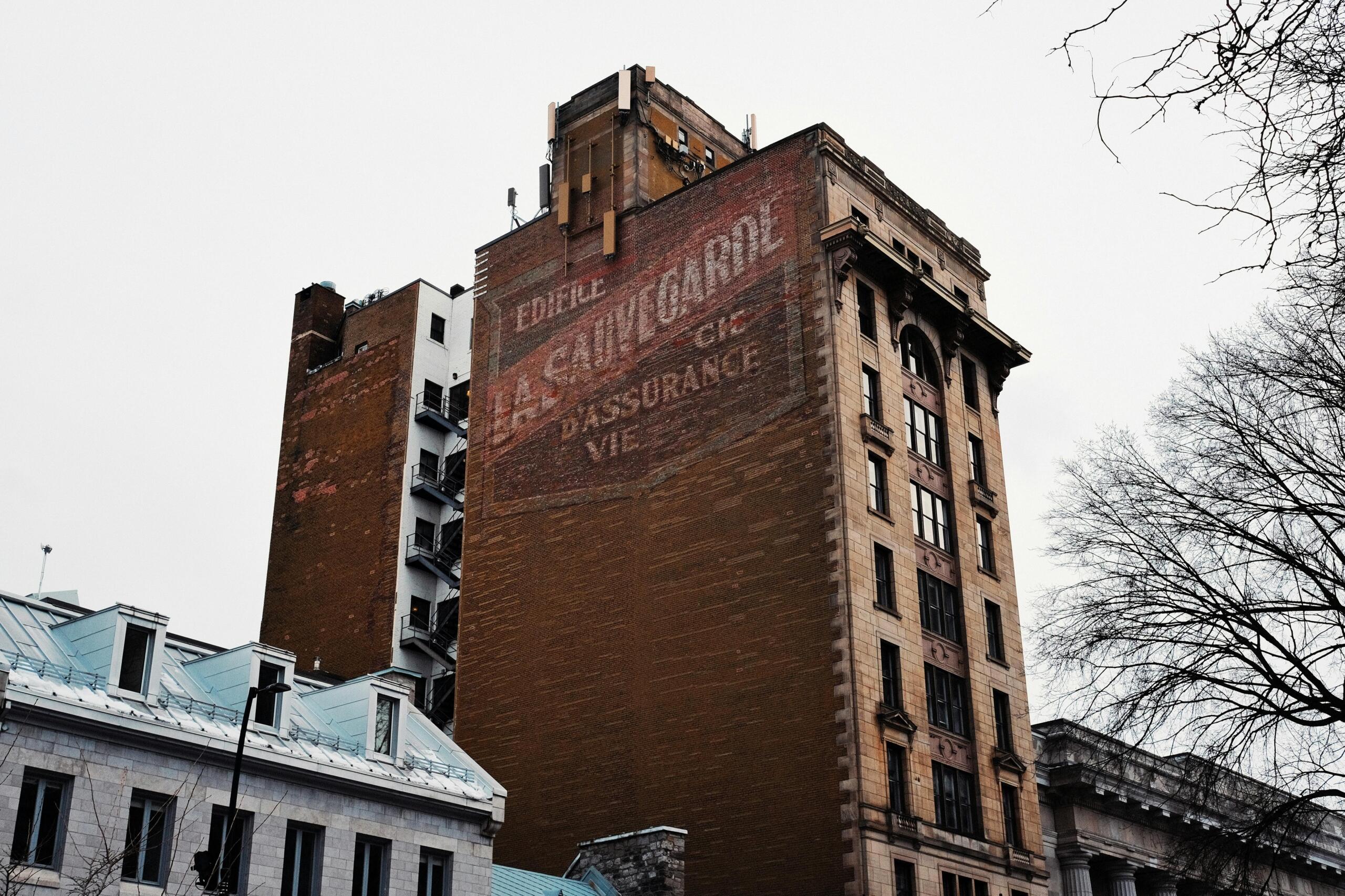 A historic building made of brick. An advertisement is painted on the side of the building.