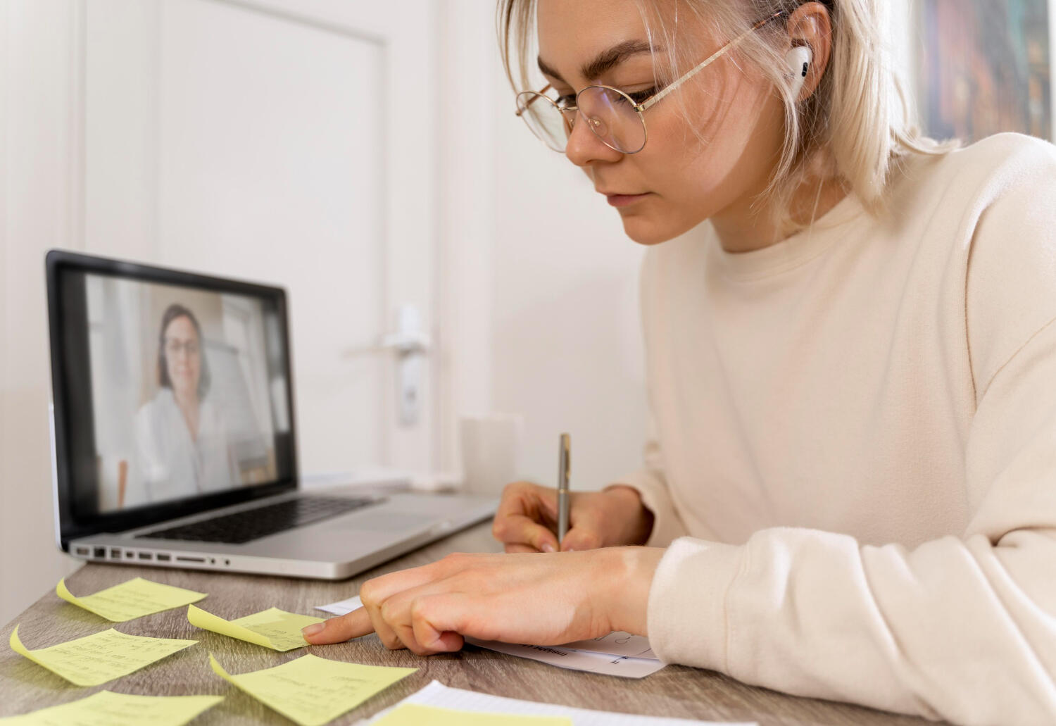 a female student taking notes while listening to an online tutor.
