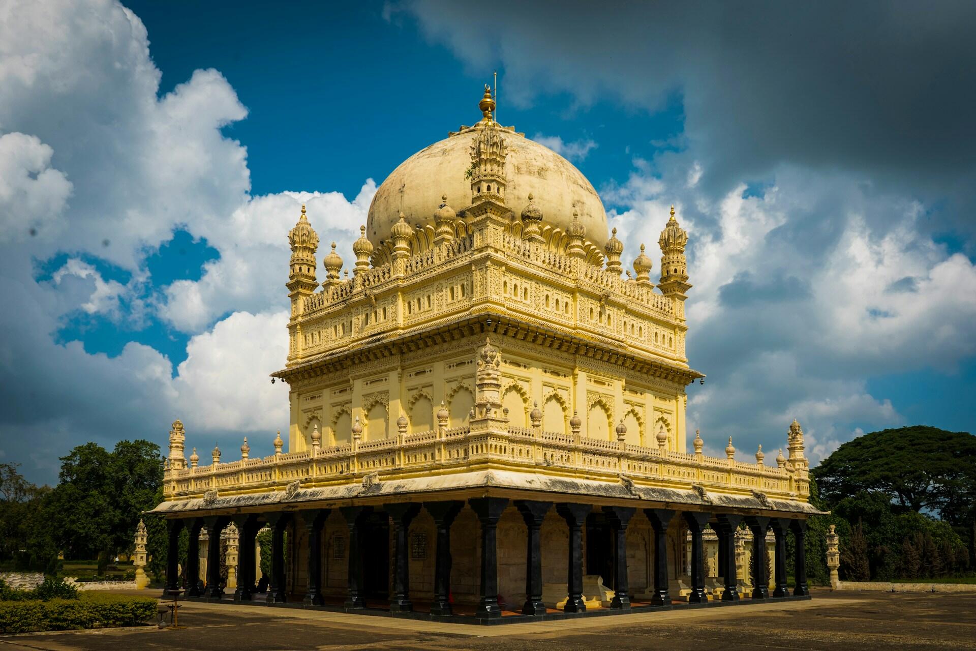 An ornate golden-domed building with archways against a cloudy blue sky.