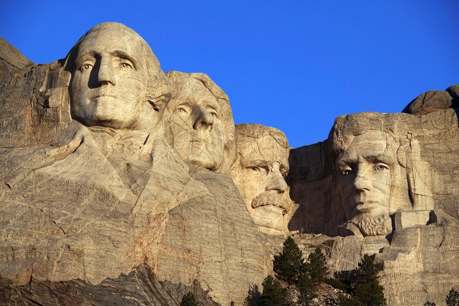 Mount Rushmore view with two covered sculptures and visible sculpture in the middle.