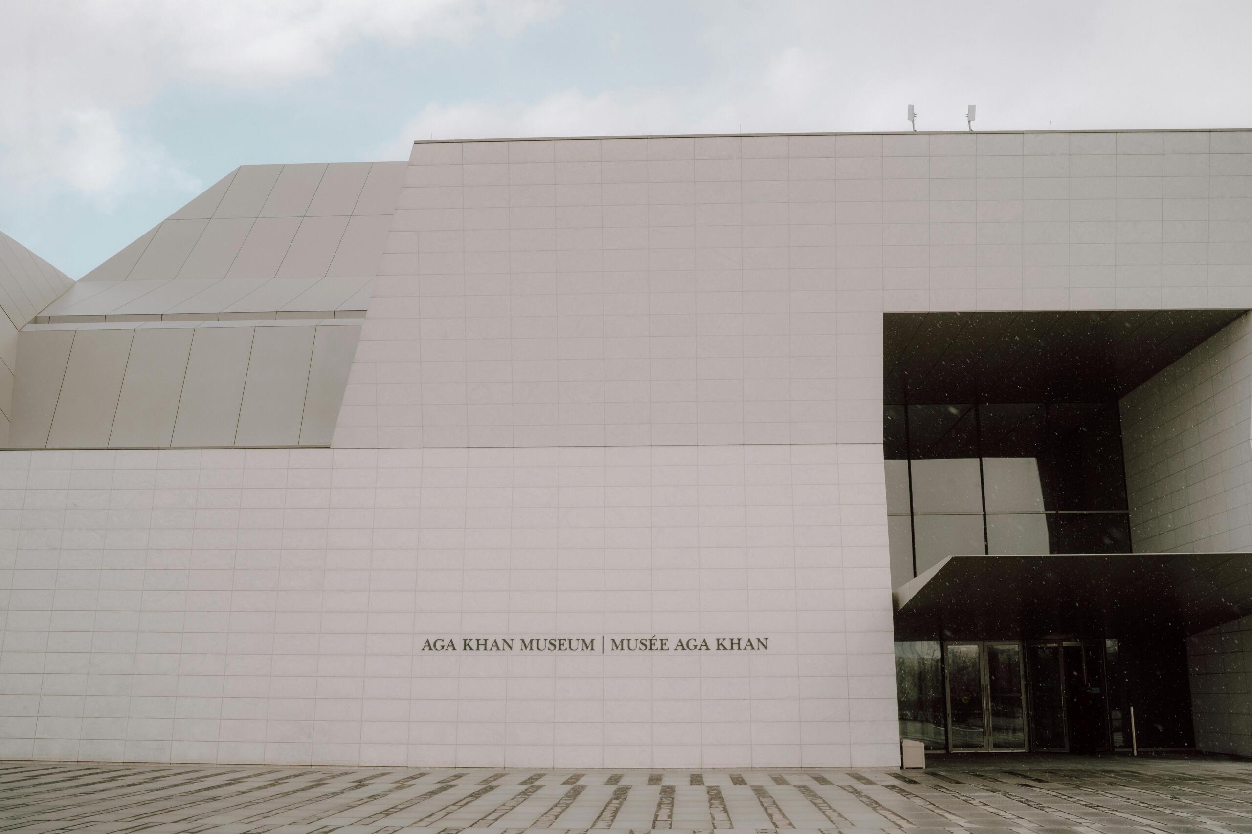 A modern building with the words "Aga Khan Museum" on the front. The sky is cloudy behind the building.