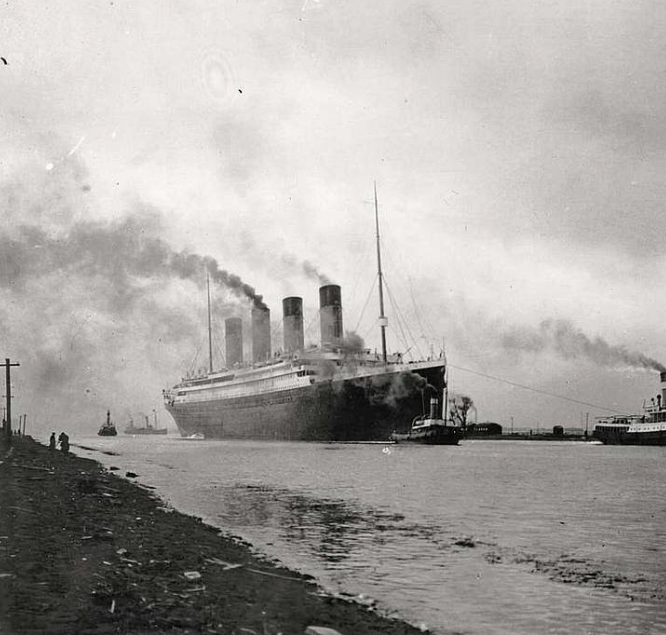A historic black-and-white photo of the RMS Titanic steaming along a river, billowing smoke, with smaller boats nearby.