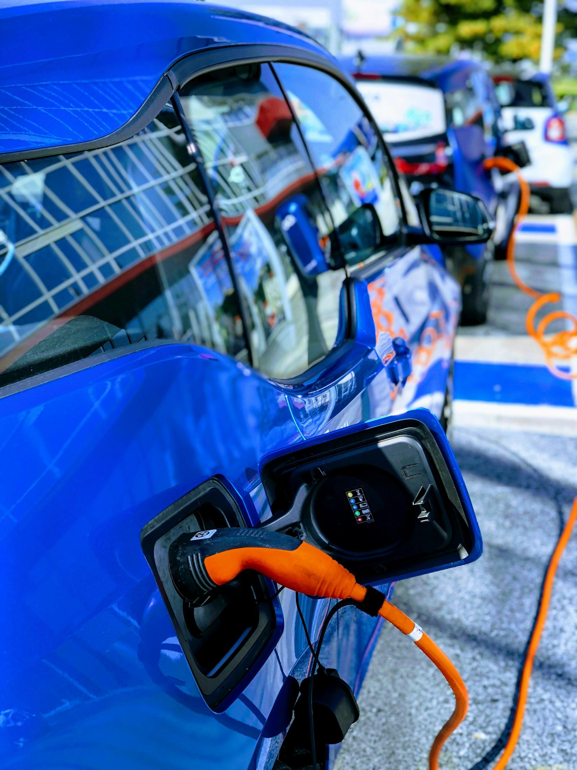 A blue electric car being charged at an EV charging station. 