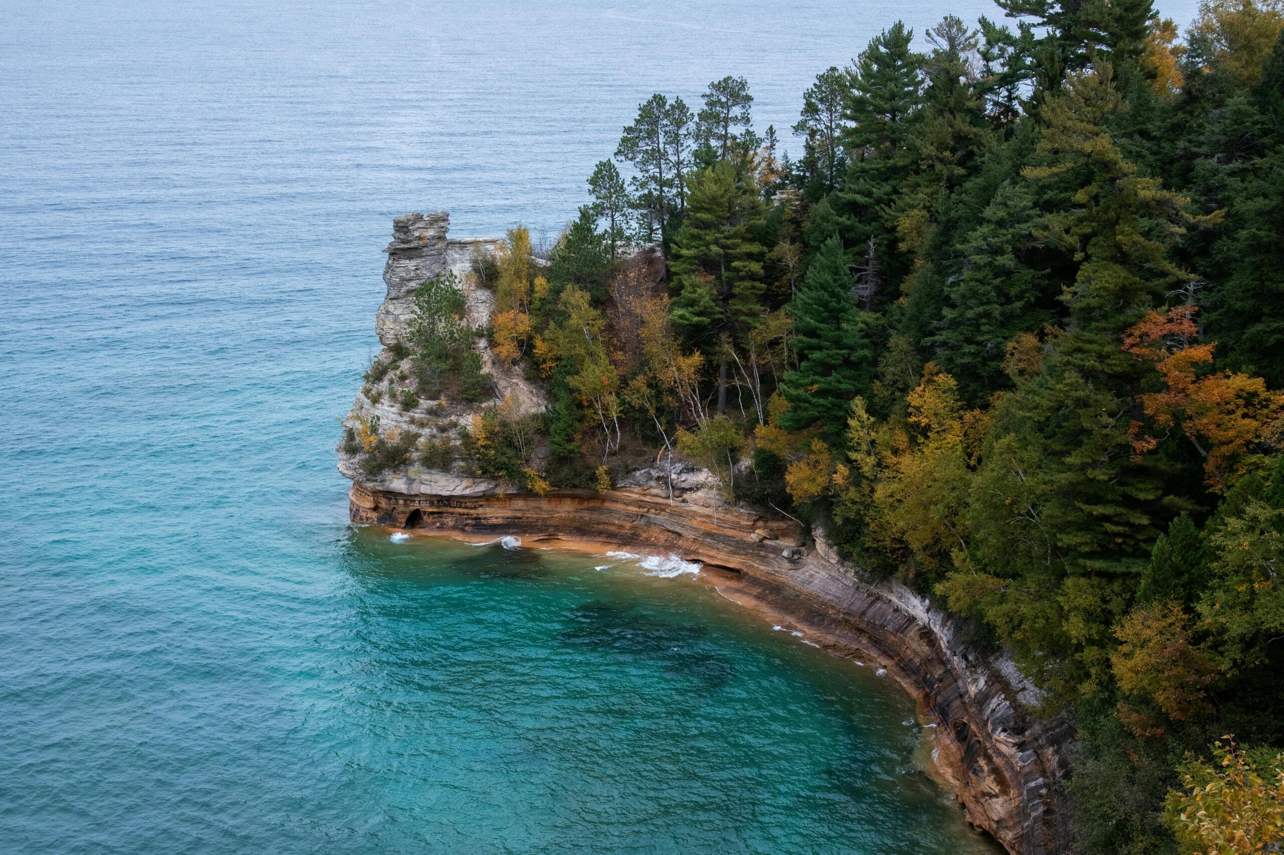 a rocky cliff juts into a clear body of water.