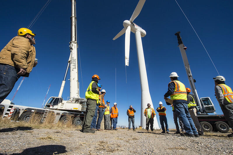 a group of wind engineers discussing and doing groundwork check for a few wind turbines. 