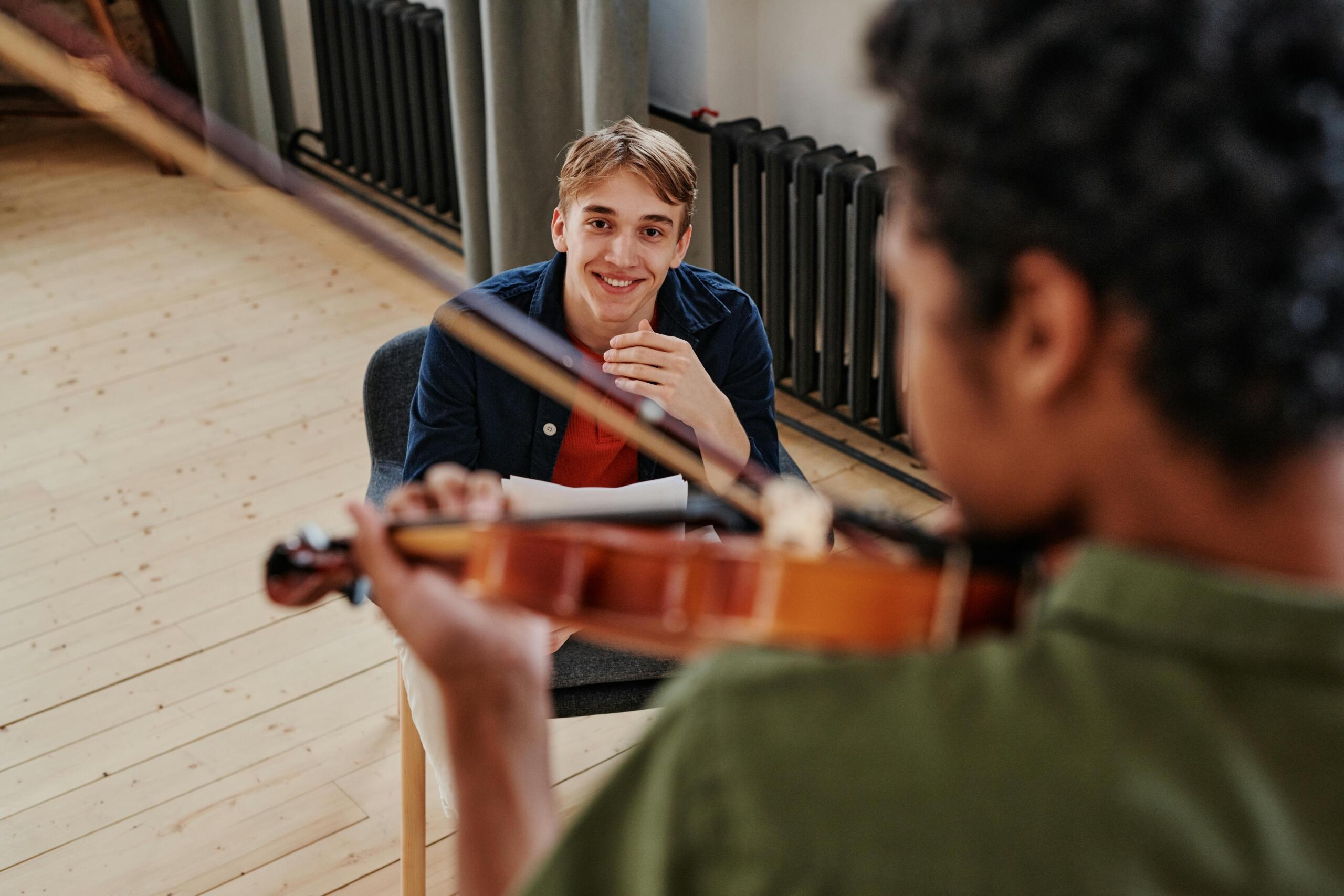 a teacher watches a student play the violin
