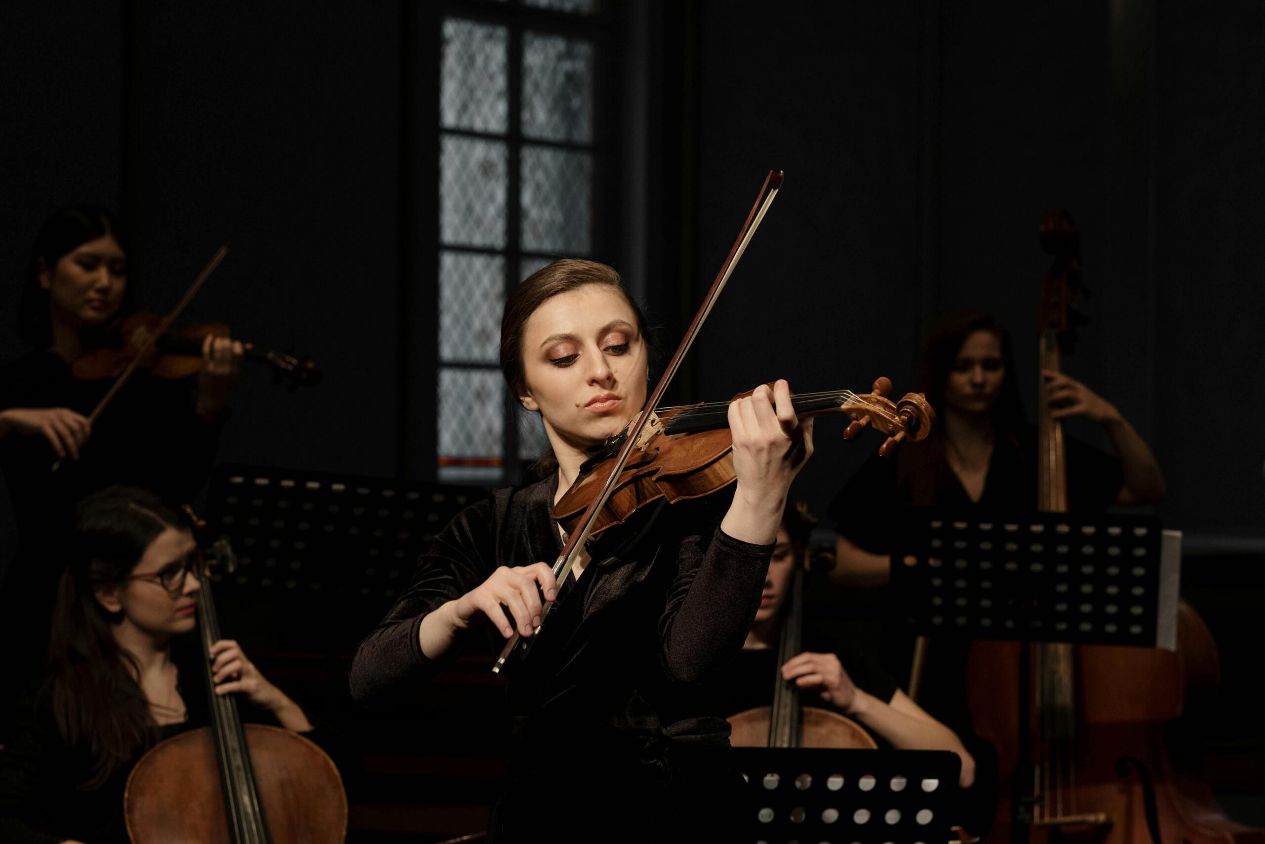 a woman in dark colours plays the violin.