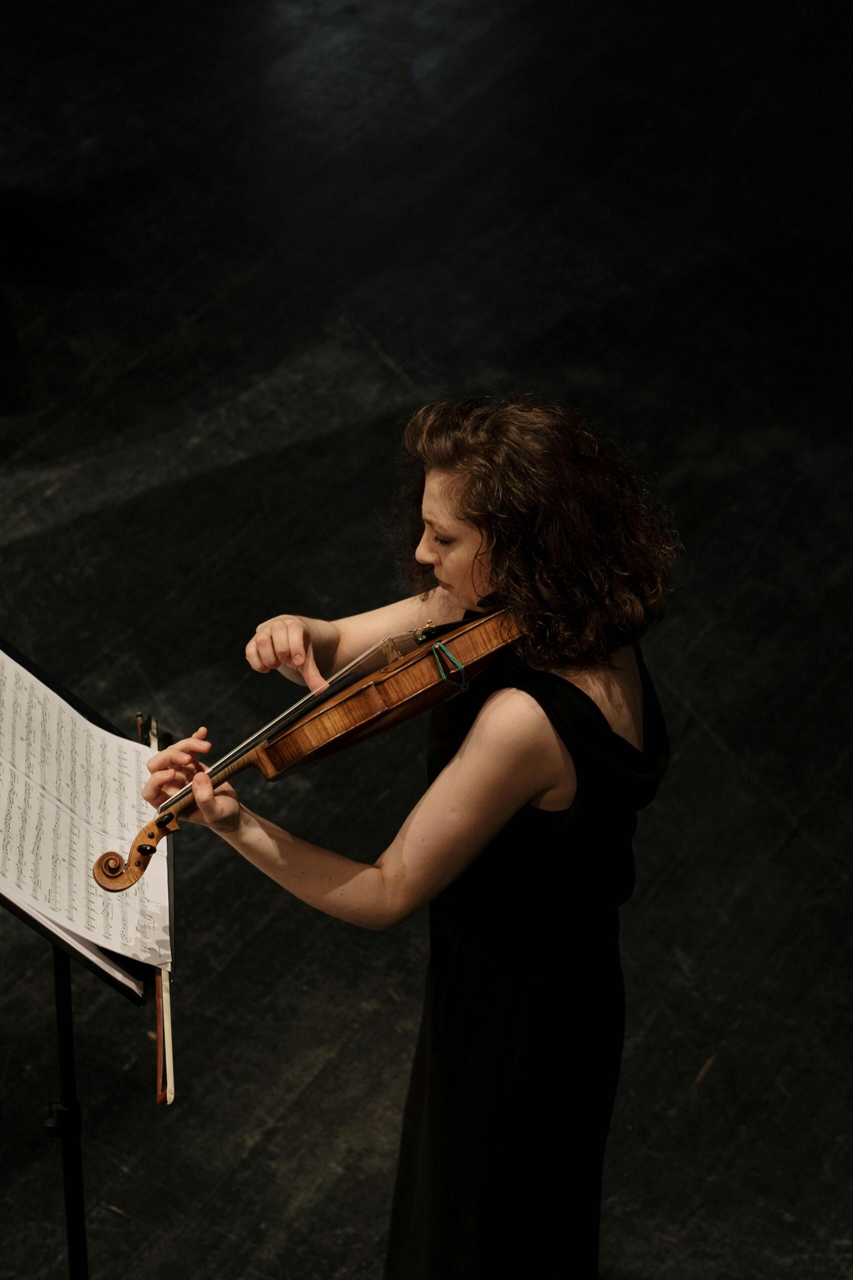 a woman wearing black plays the violin.