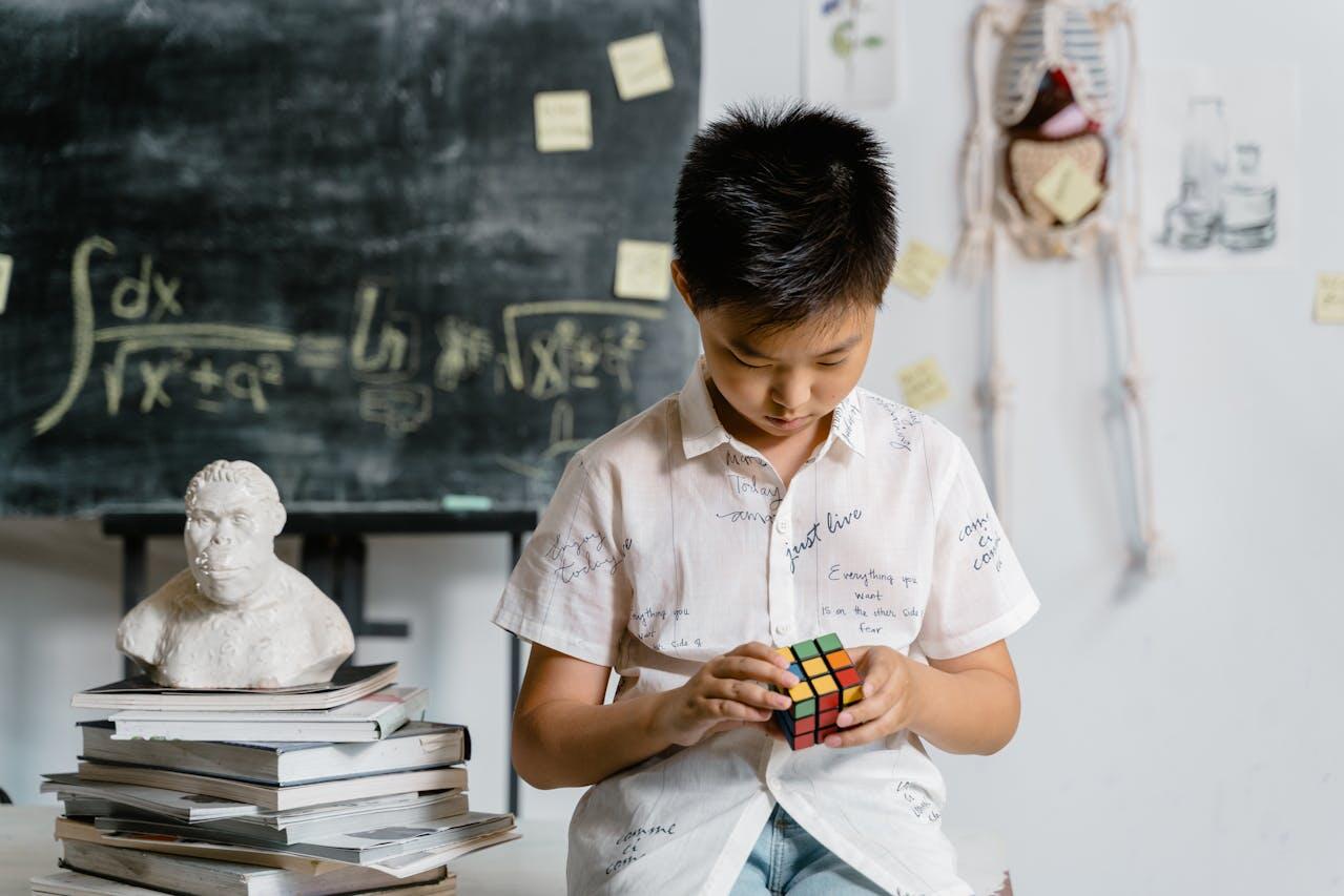 a boy playing withh a rubik cube in front of a blackboard with math formulas