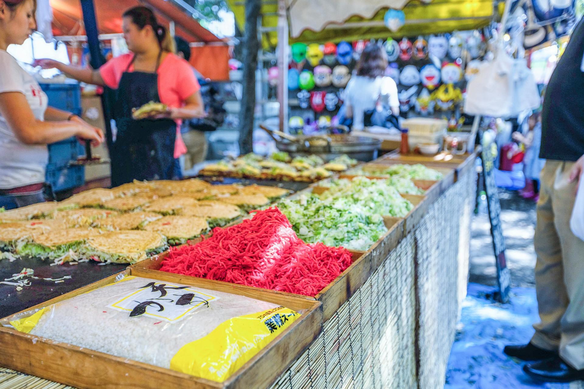 A vibrant market stall displays various fresh ingredients, including colorful noodles, vegetables, and packaged rice, inviting culinary creativity.
