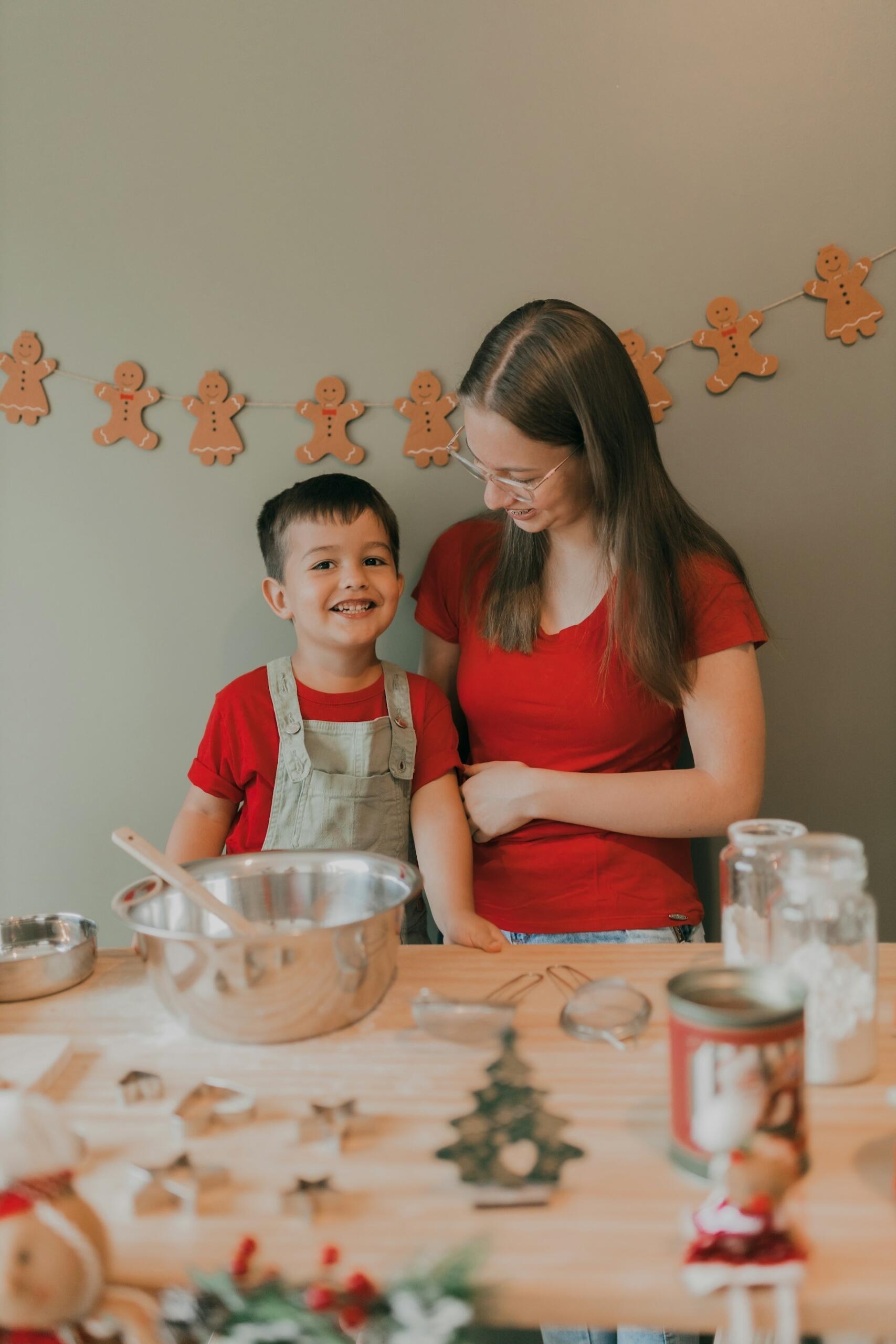 a young boy baking with a female adult in a kitchen