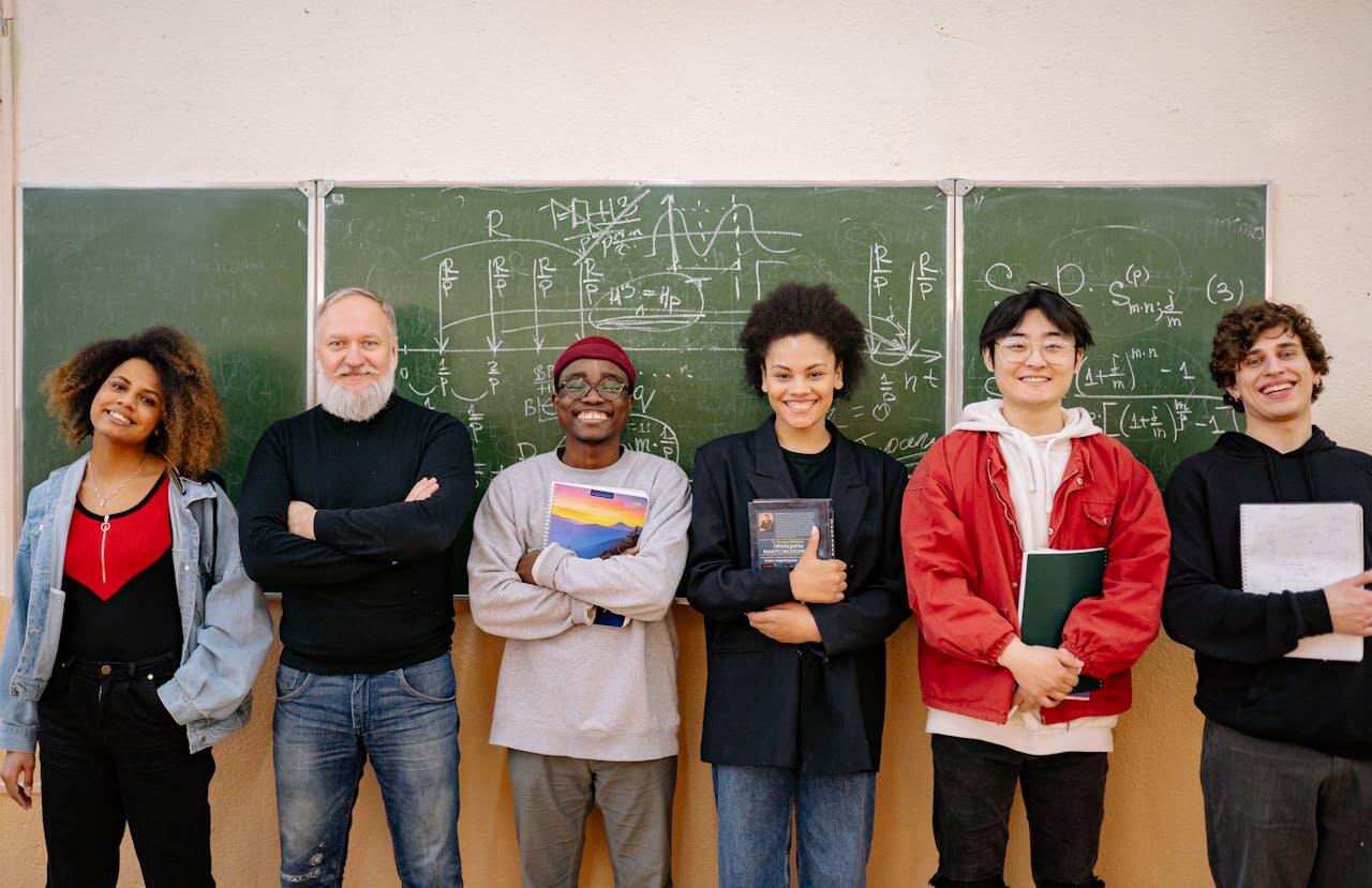 a group of students standing with their teacher with a blackboard with math formulas behind them.