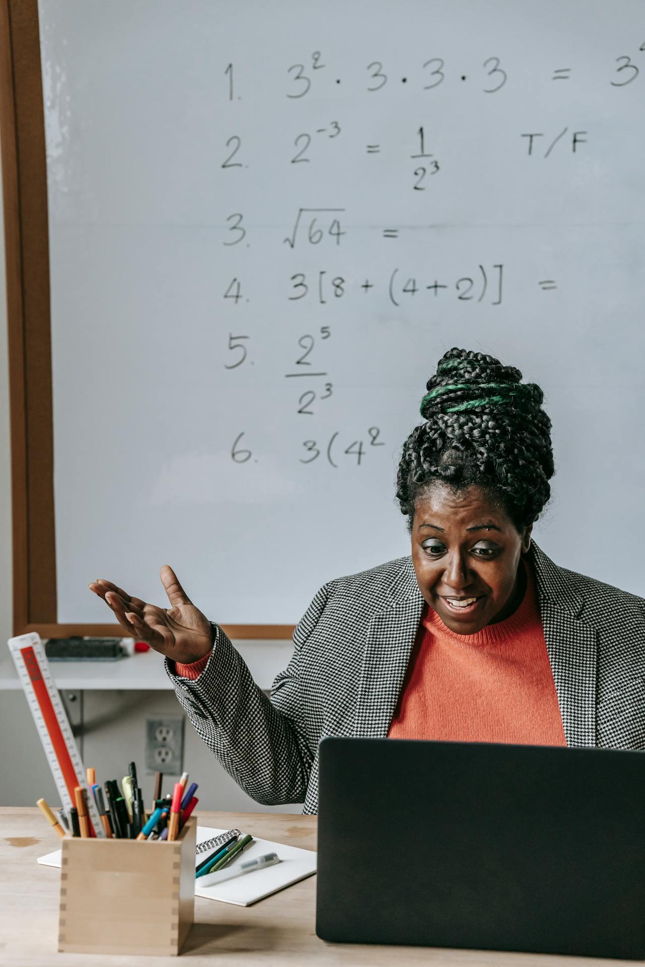 Excited black teacher explaining math lesson online with laptop