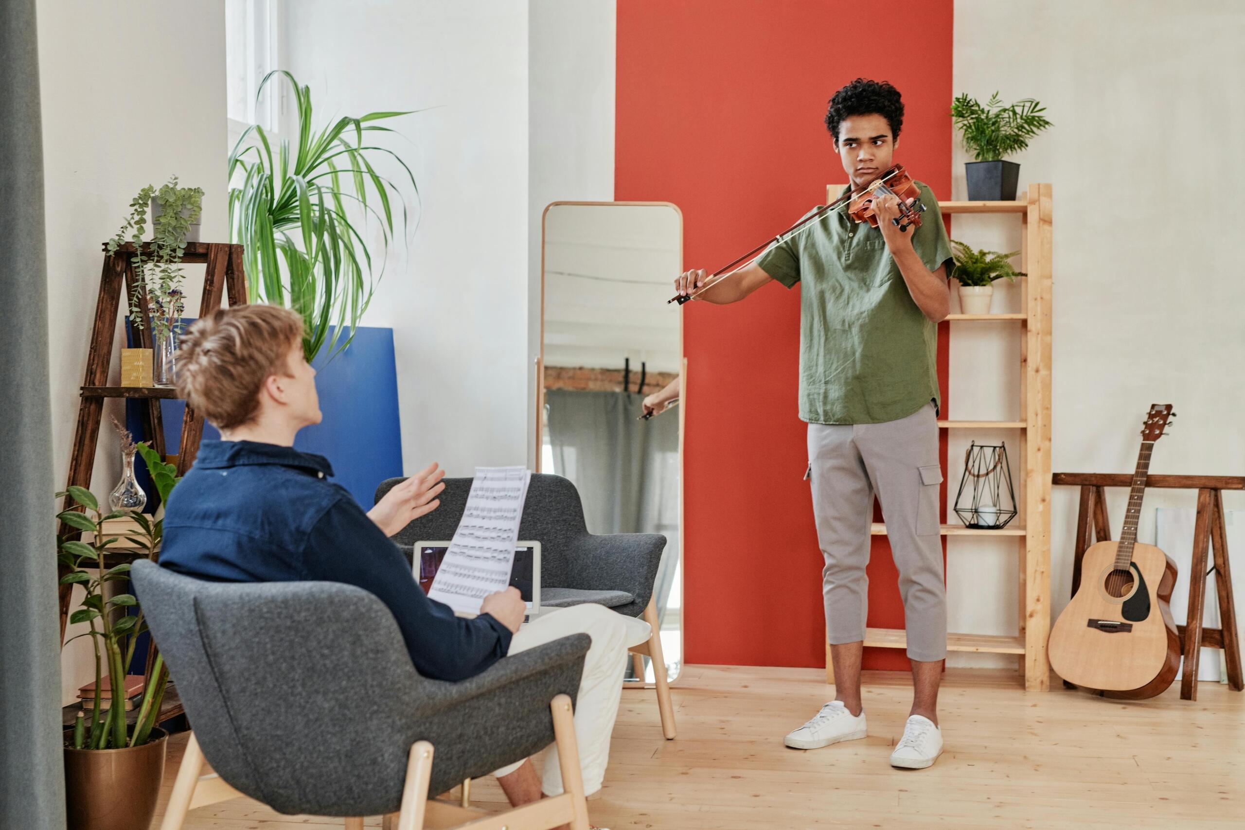 a student violinist plays in front of his teacher.
