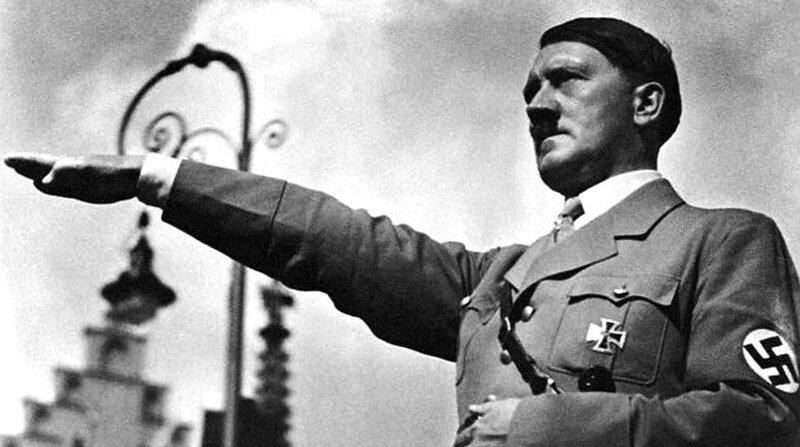 A soldier in a Nazi uniform raises his arm in a salute, with a backdrop of historical architecture and cloudy skies.