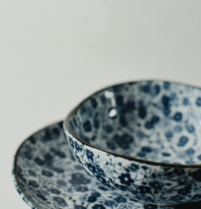 Stacked ceramic bowls with intricate blue floral patterns against a light background, showcasing elegant craftsmanship.