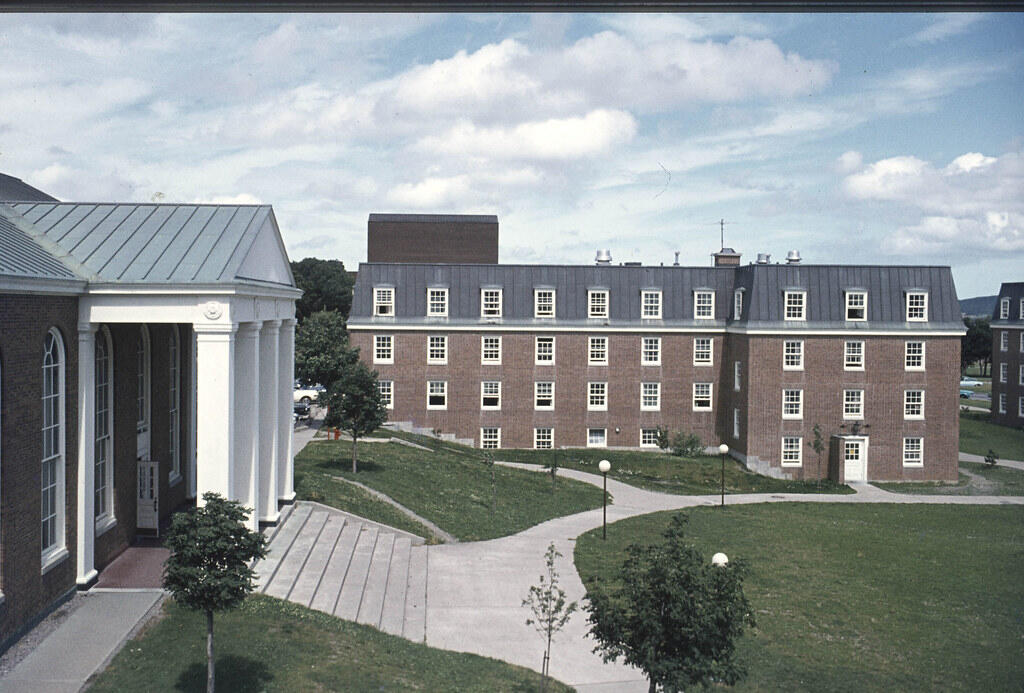 Memorial University campus in Newfoundland, featuring red-brick academic buildings and green lawns under a blue sky.