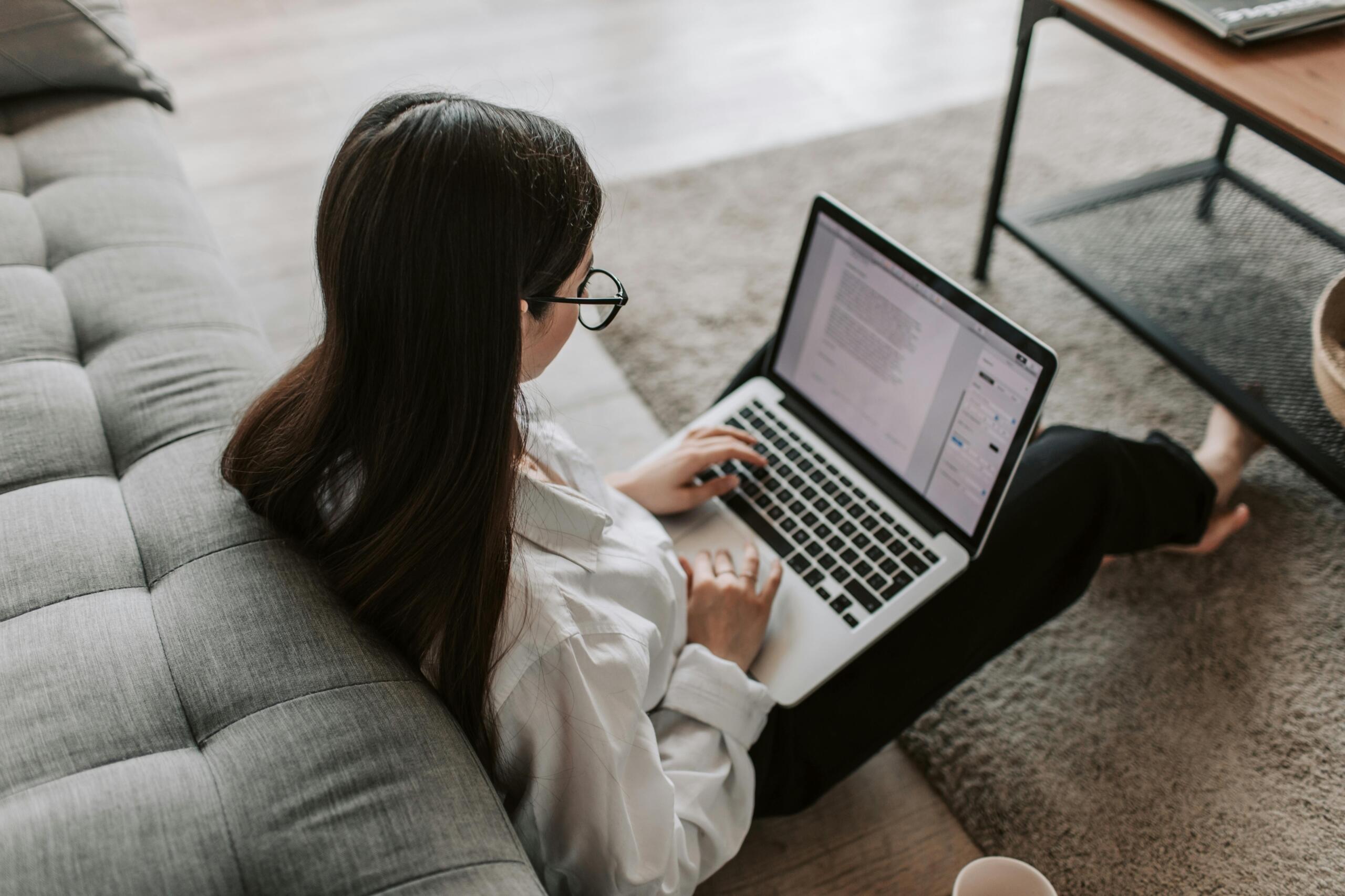 A business student working on their laptop at home, focused on an online class or assignment in a cozy study space.
