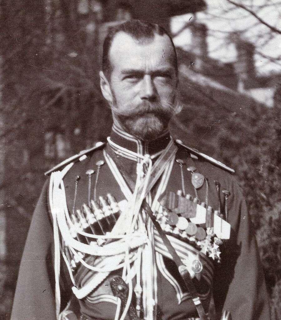 A man in a ceremonial military uniform adorned with medals and decorations, set against a blurred natural background.