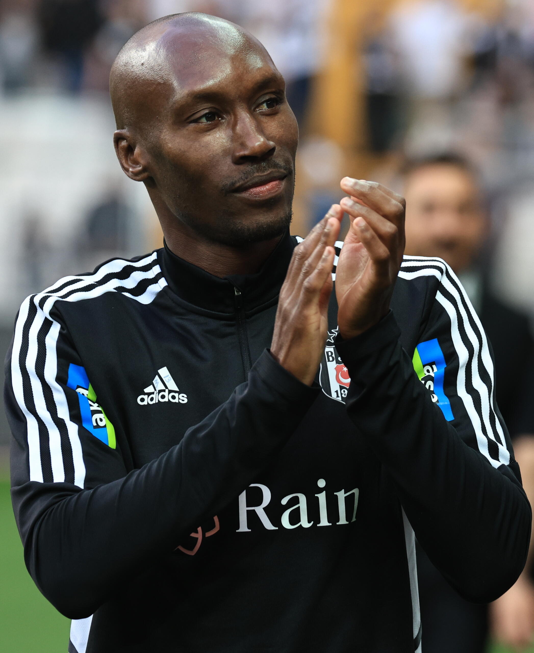 Atiba Hutchinson clapping in a Besiktas training jacket, acknowledging fans on the pitch.