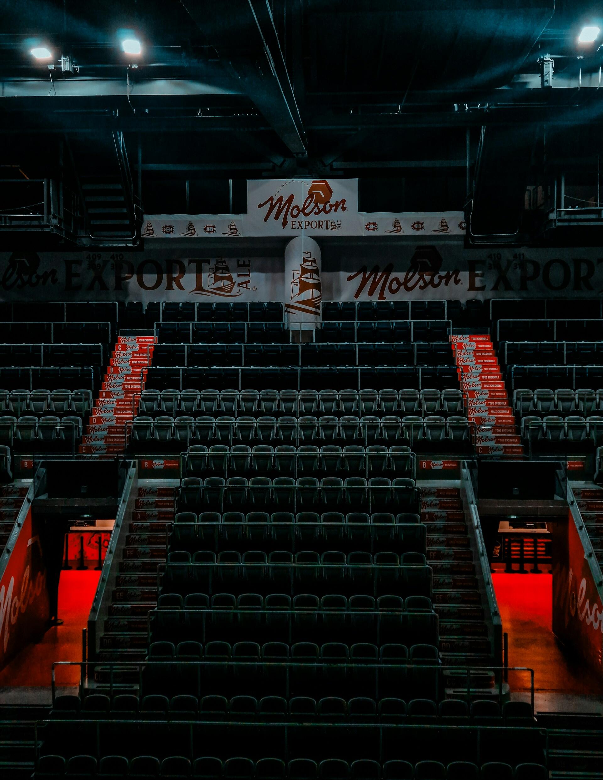 Empty arena seats illuminated by red accents, featuring Molson Export branding on the walls and stairways.